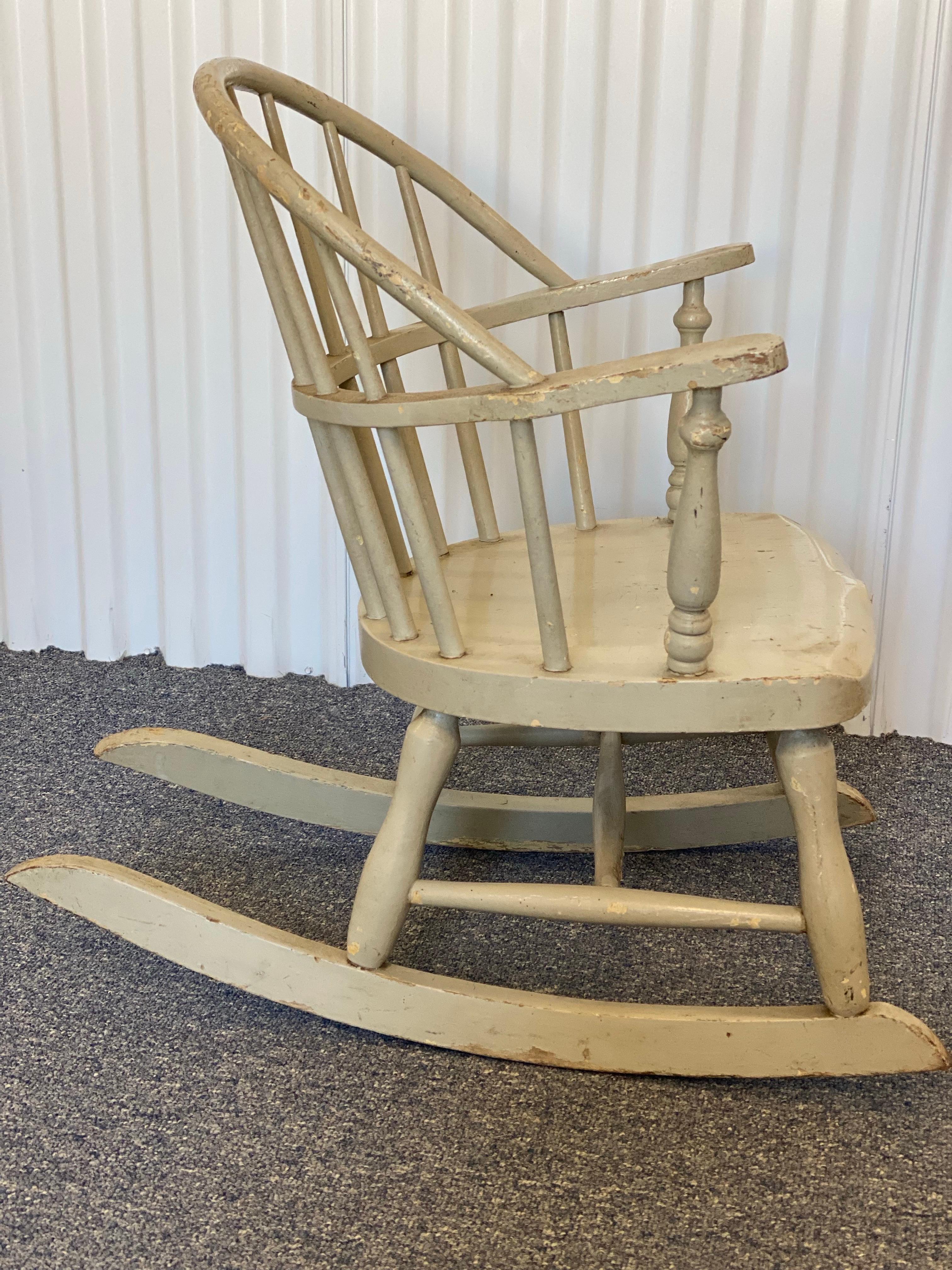 American Grey Painted Wood Windsor Child’s Rocking Chair, 20th Century

A Windsor back in a painted grey finish with pain seat on rockers. This rocking chair is for a child. This child-sized rocking chair exhibits characteristics of early
