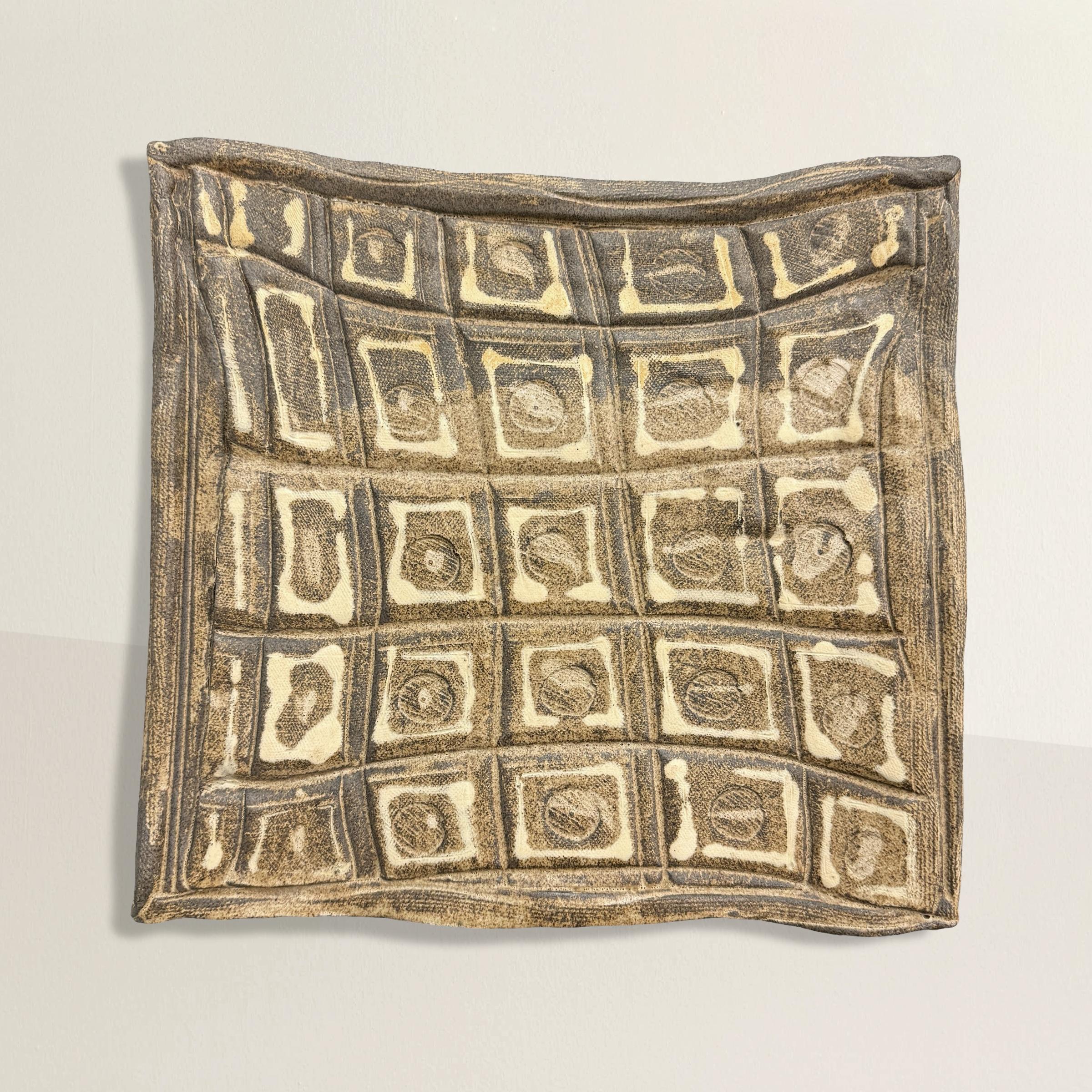 This late 20th-century American hand-built slab ceramic tray is a striking fusion of artistic craftsmanship and practical utility. Its undulating edges add a touch of organic elegance, drawing the eye to the intricate pattern of repeated unique