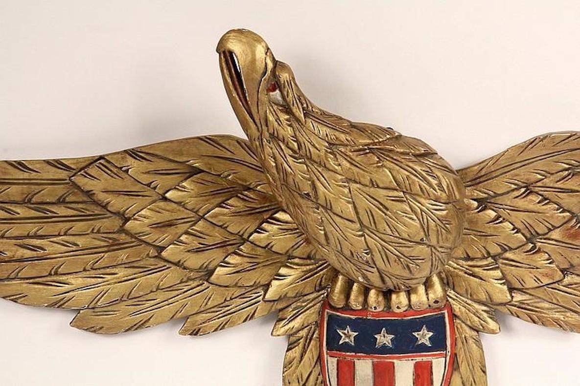 This is a hand-carved and painted American folk eagle in the style of John Bellamy. The eagle has spread wings and head turned to its right. The artist, unknown, carved the eagle with exceptional detail, especially in the eagle's wings.

The eagle