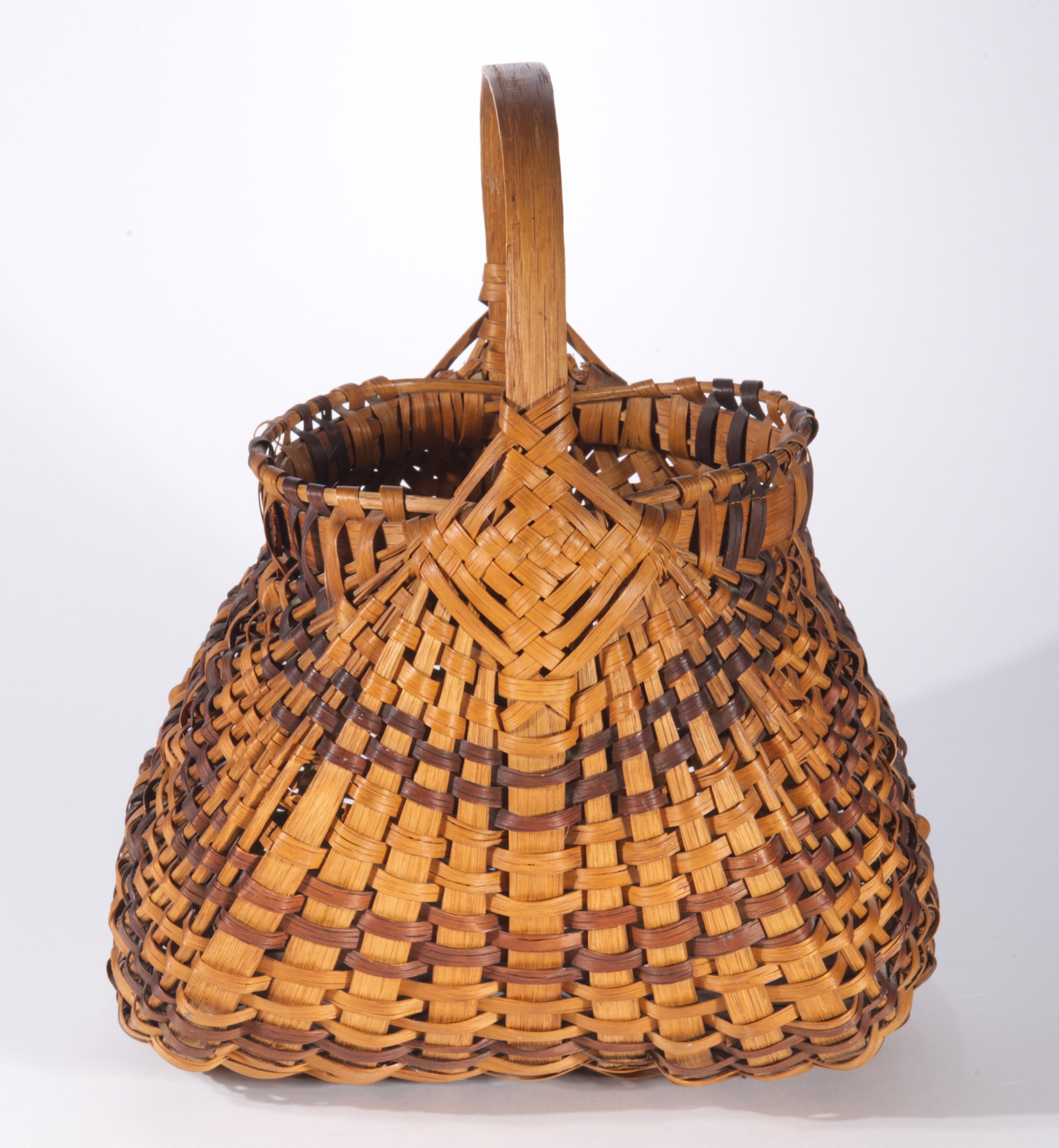 Vintage or antique gathering basket features traditional rib or buttocks shape with the bent wooden ring rim and handle. The plaited splints are carefully interwoven to carry the design along the body of the basket. The basket is decorated with a