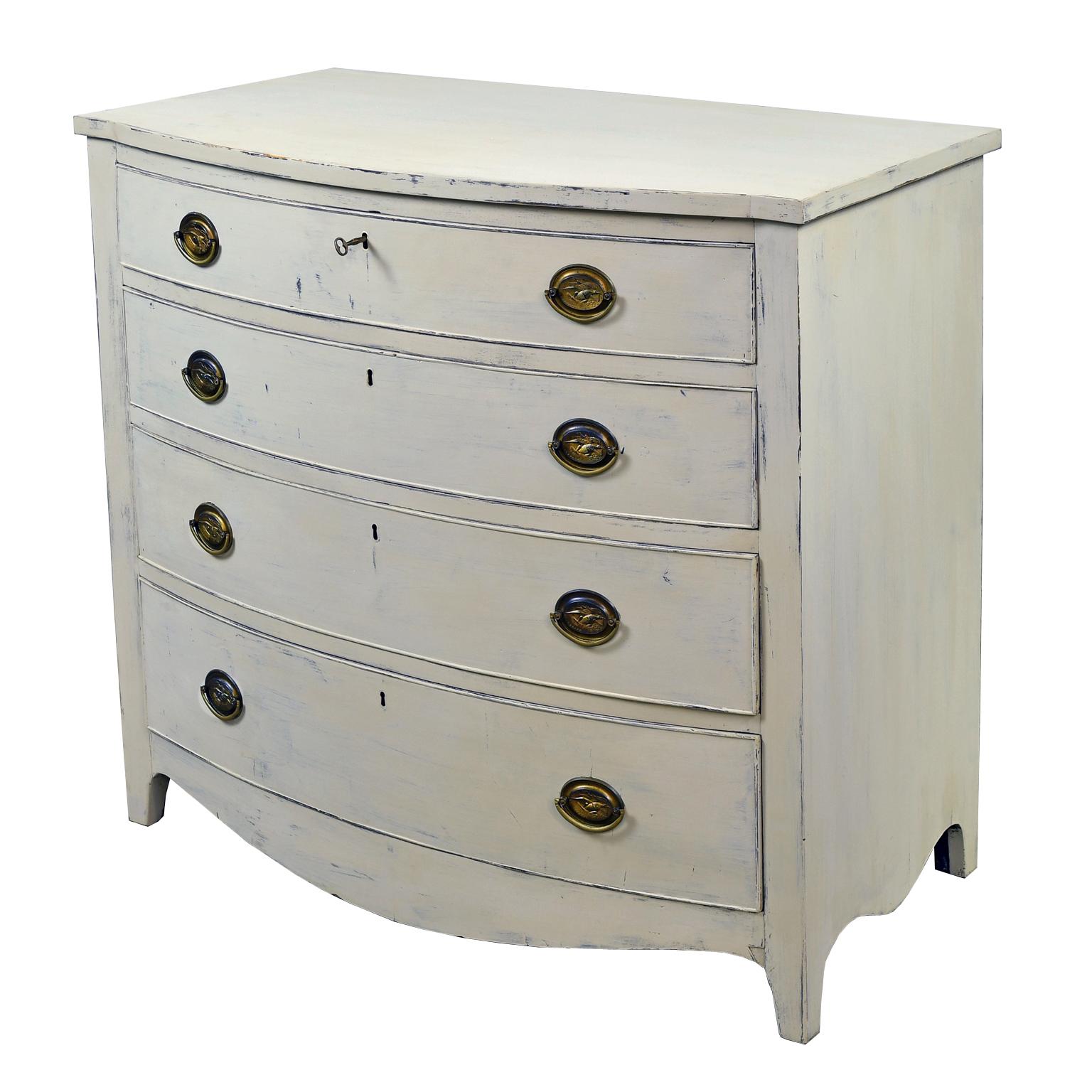 A lovely American Hepplewhite chest with bowed front, sculpted apron and tapered square feet offering four drawers of staggered depths with period brass plates and pulls. The oval escutcheon plates are embossed with a flying bald eagle clutching in