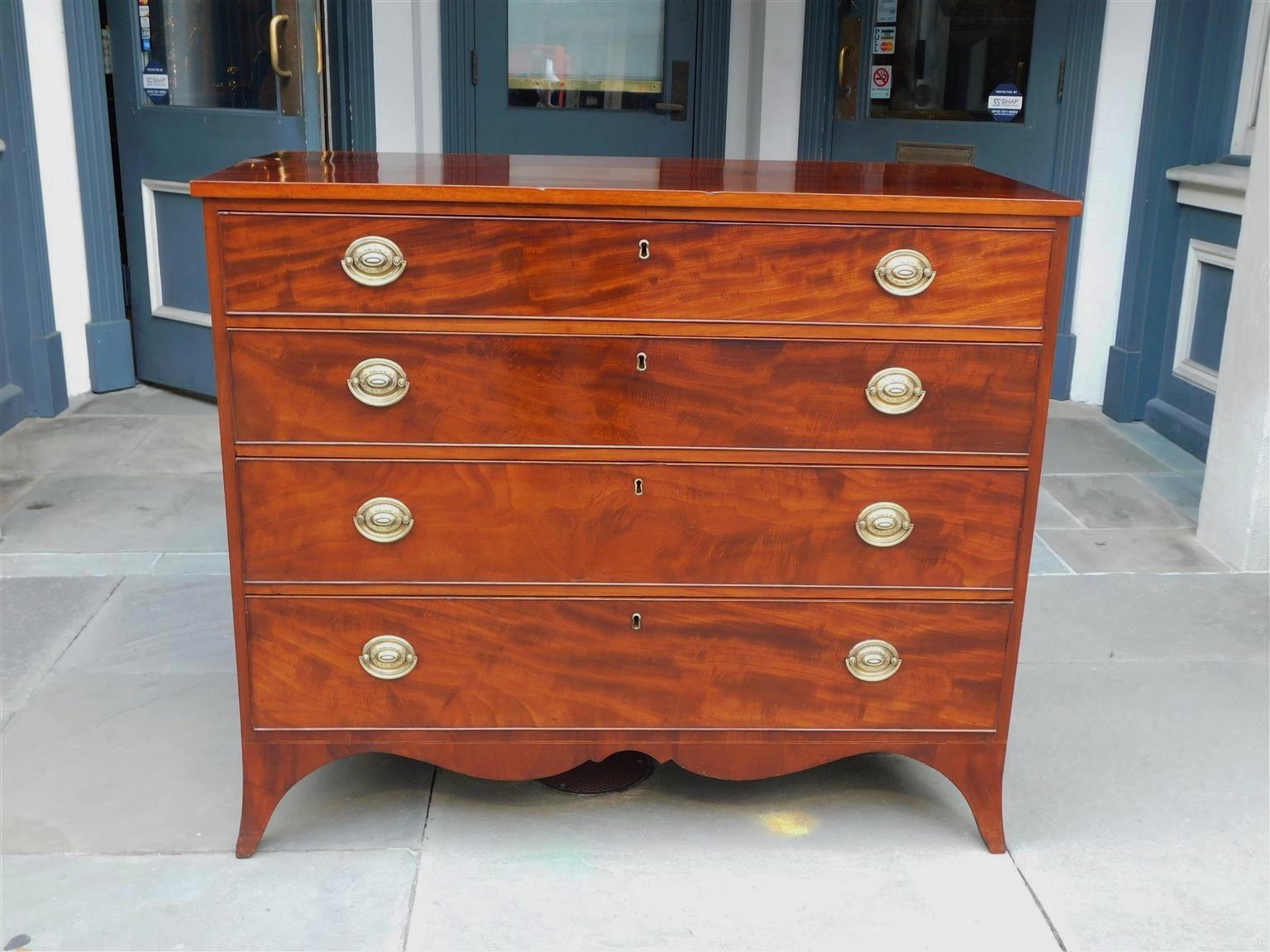 American Hepplewhite mahogany chest of drawers with a molded edge top, four graduated drawers with original oval brasses, carved scalloped skirt, and resting on the original splayed feet. Early 19th Century Secondary wood consist of tulip poplar.