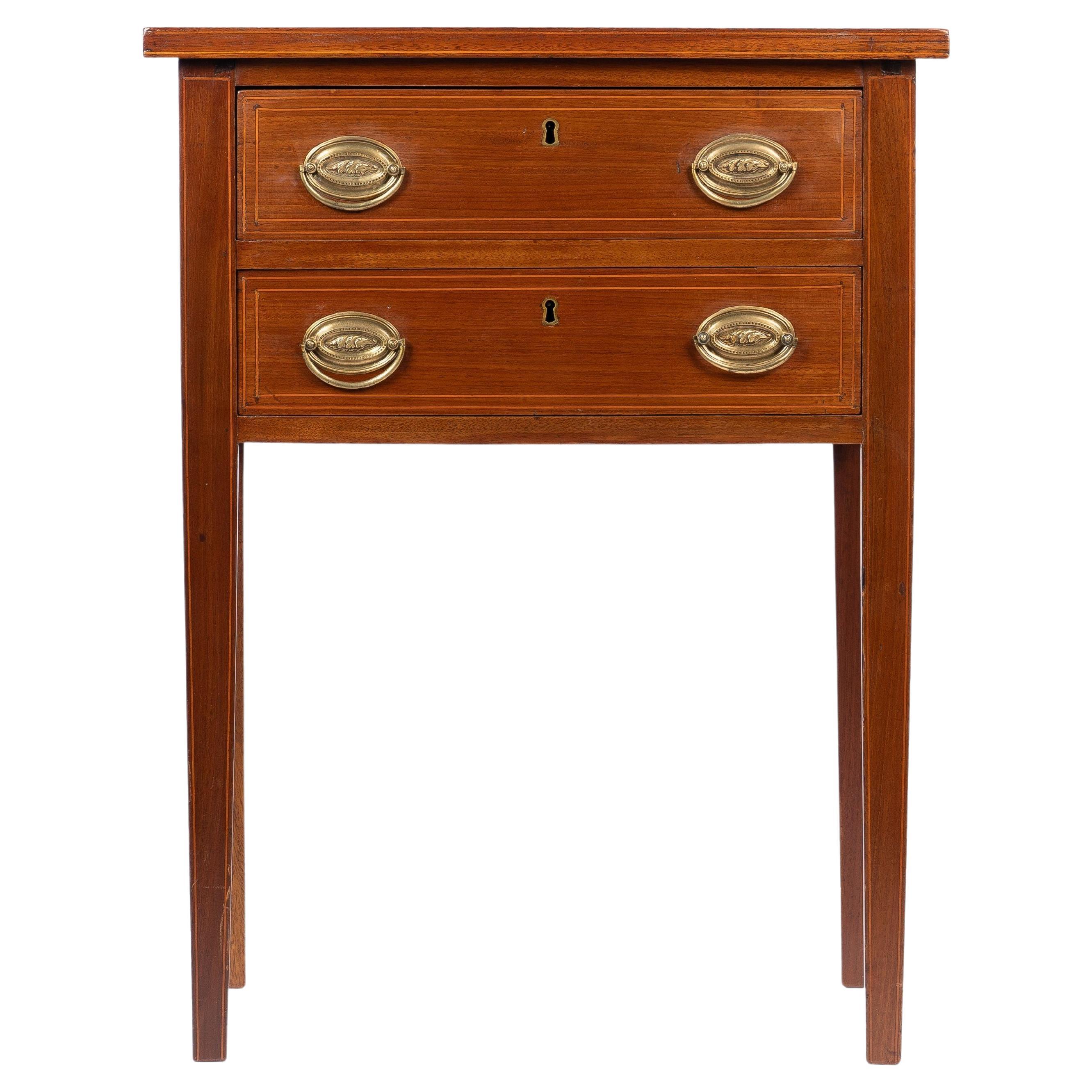 American Hepplewhite mahogany two drawer stand. There is a string inlay on the edge of the top, around the drawer fronts and down the front legs. The drawers are fitted with paired, oval stamped brass back plates, and cast brass posts and bail