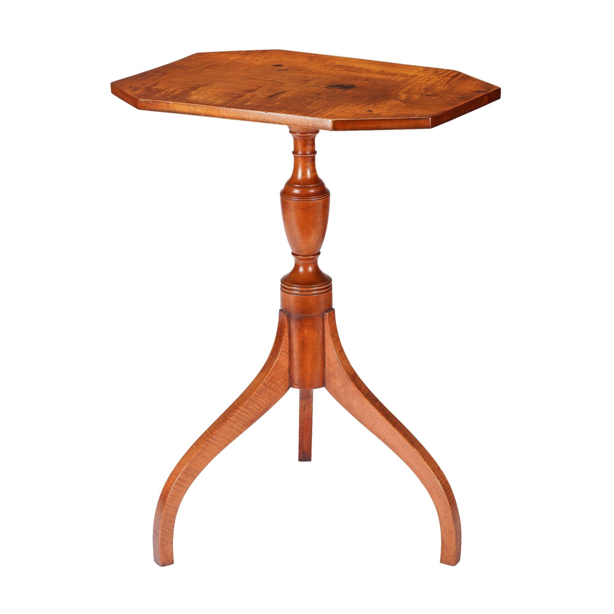 American figured maple octagonal top candle stand with an urn form turned baluster resting on arched tripod spider legs. The single board table top is fixed to the base with a chamfered cleat. Traces of original oxide red stain.

Upper Connecticut