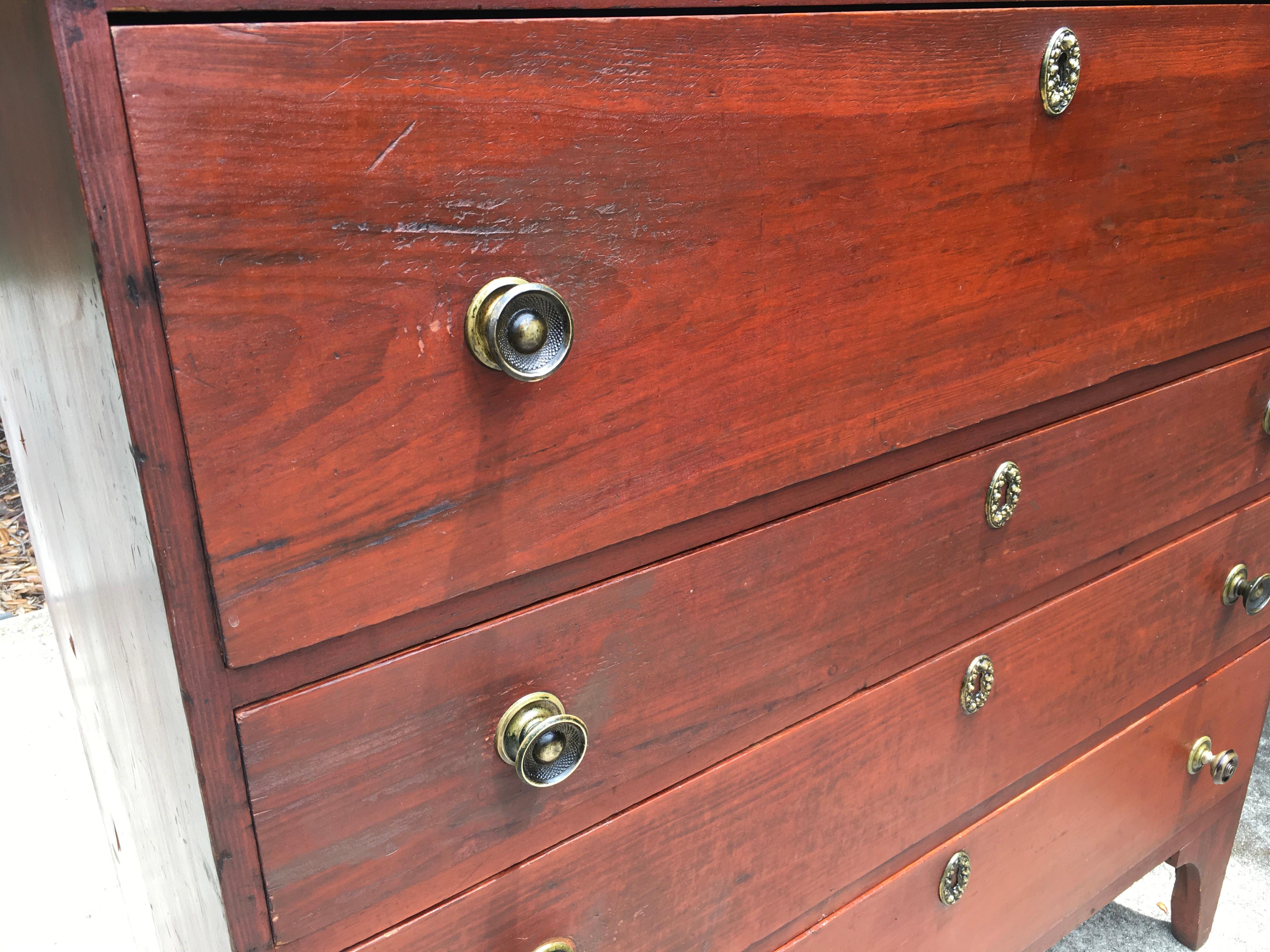 Country Hepplewhite four drawer chest in original red paint of New England origin dating from 1800-1820 standing on tall arched feet. This chest is a fine piece of federal era Americana and is constructed of White Pine and Poplar and retains it’s