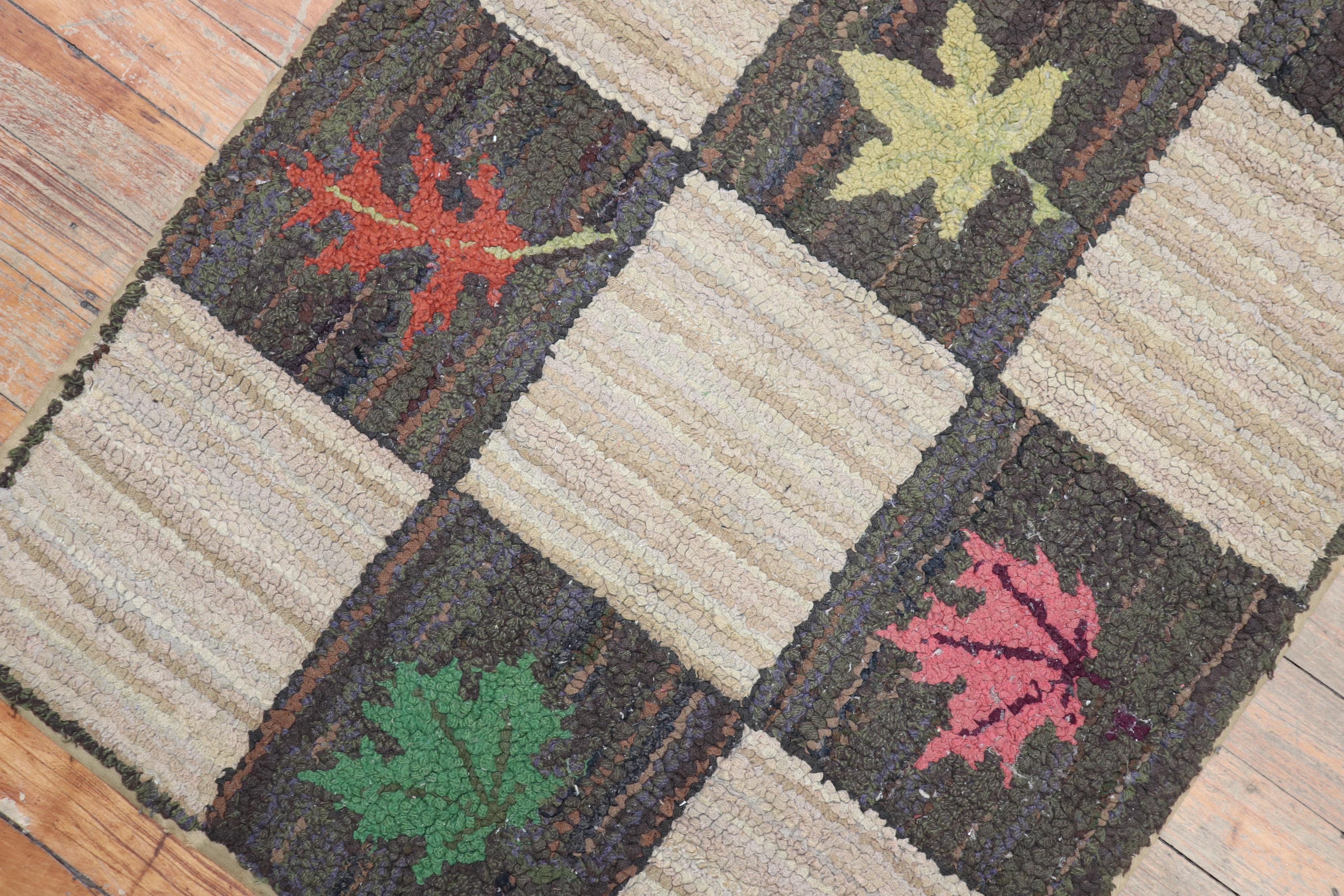 A handmade decorative American hooked rug from the middle of the 20th century with an assortment of leaves on a repetitive box pattern on a gray and beige ground

Measures: 2' x 2'11'.
