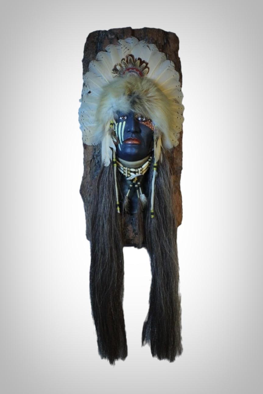This is a sculpture depicting the head of a Native American crafted from natural materials, imparting authenticity and a connection to the land and indigenous culture. The head, carved from wood, showcases refined artisanal skills with carefully