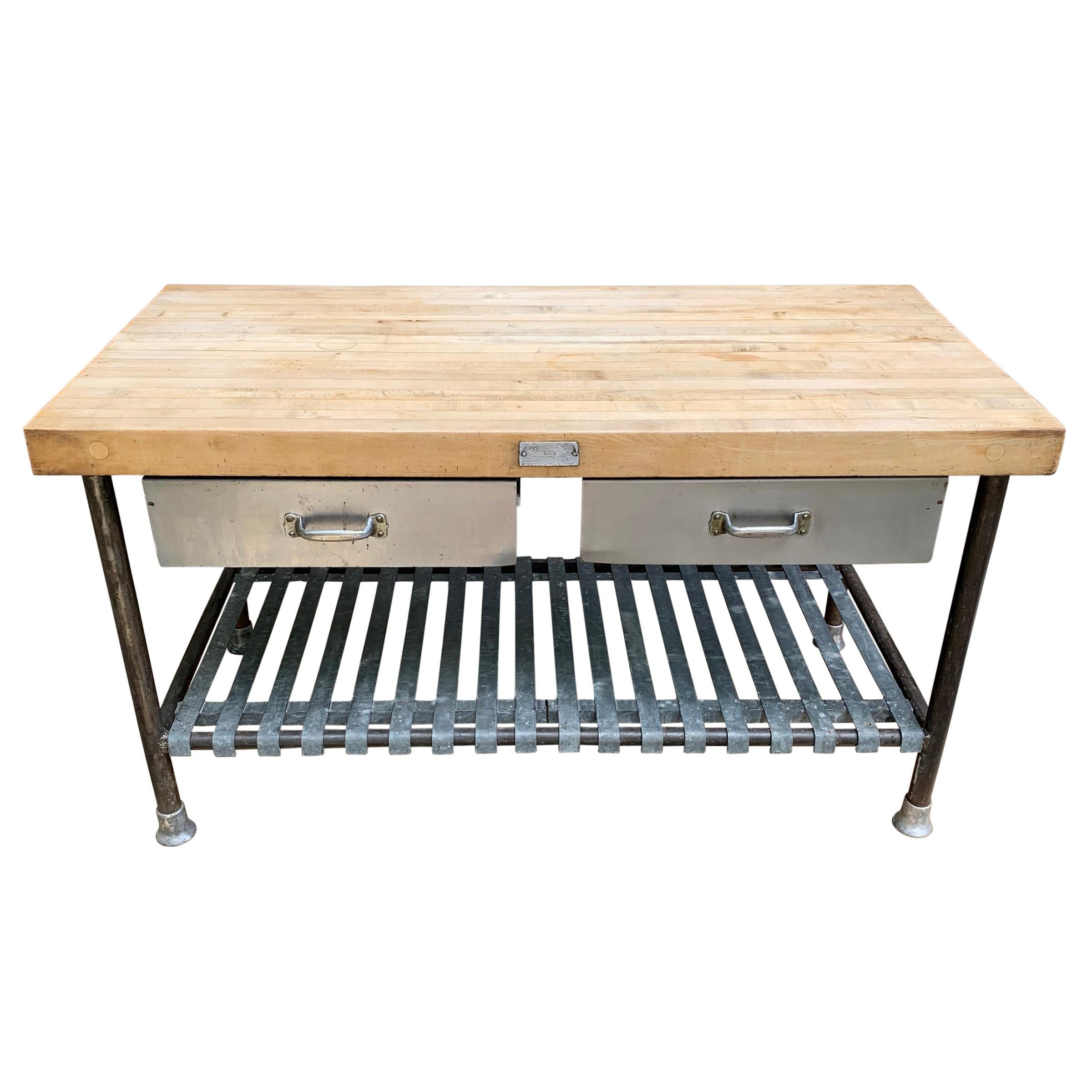 A fantastic mid-20th century American industrial table with a three inch thick maple butcher block top set on iron legs with removable galvanized steel slatted shelves and two drawers that can be locked in needed. This would make the most perfect