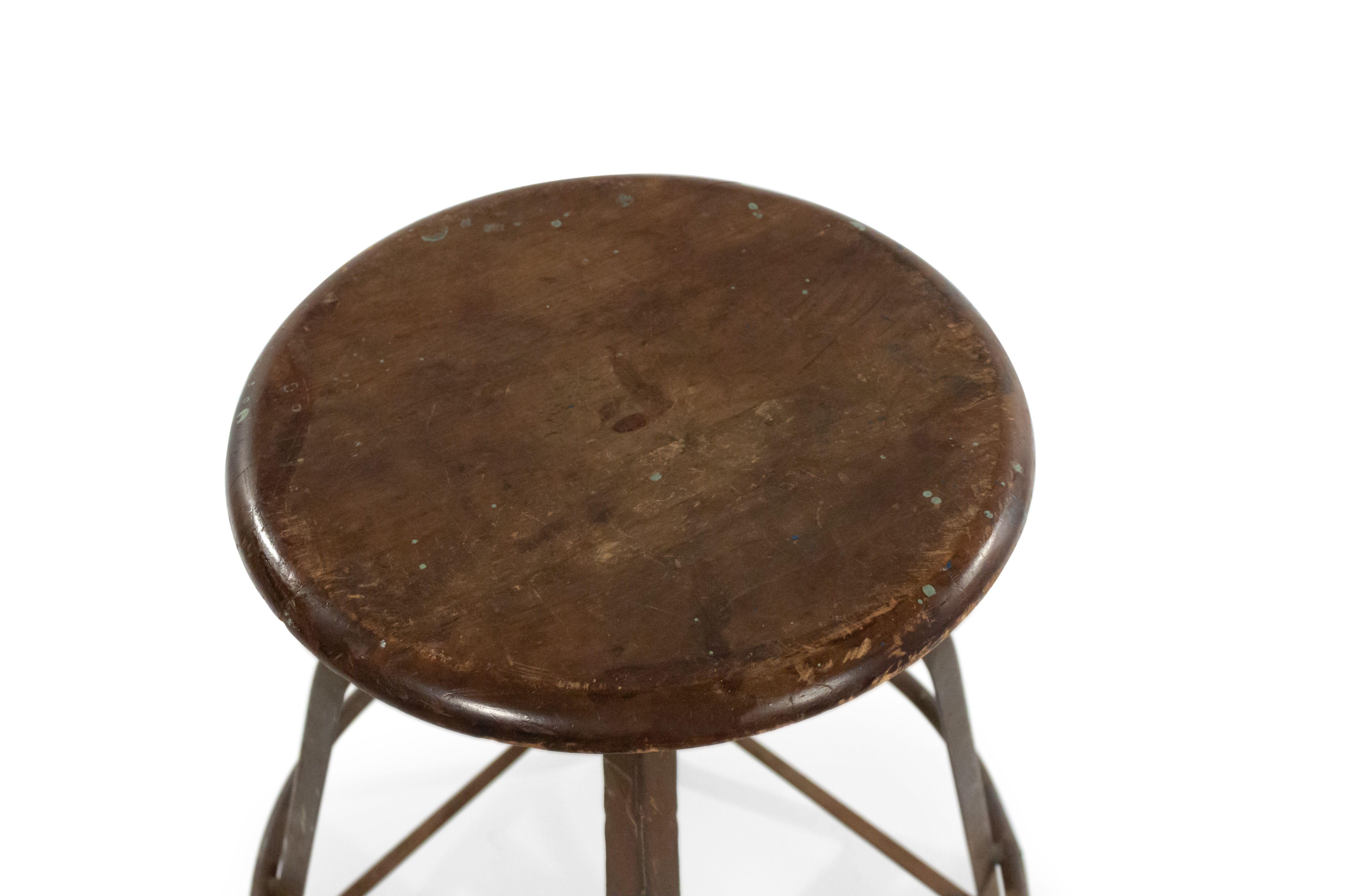 American 1940's industrial metal stool with a natural wood round top with an adjustable seat heat and a round foot rest.
     