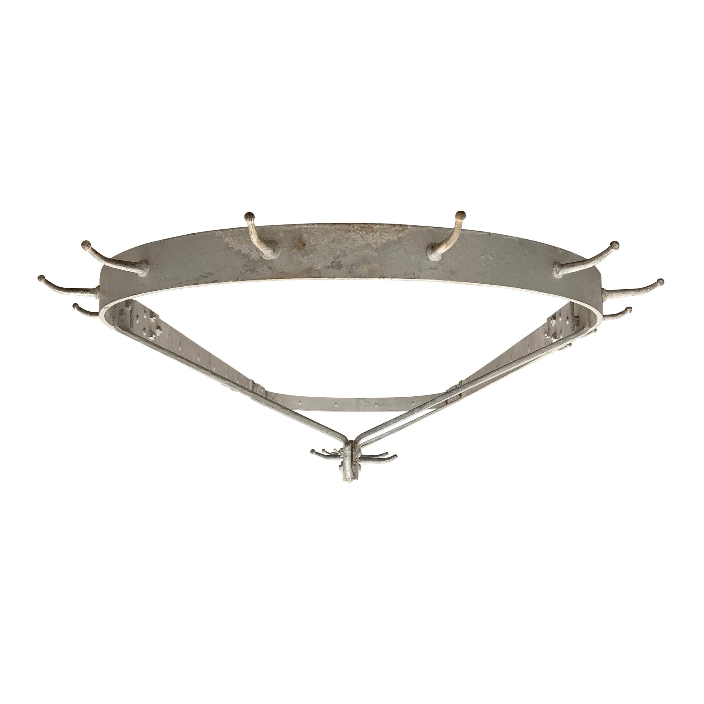 A wonderful American industrial steel pot rack with fixed hooks both inside and outside of the oval frame, and an old silver chipped paint surface. Perfect for a large kitchen, but could also be suspended in a cool entry way and used for hats and