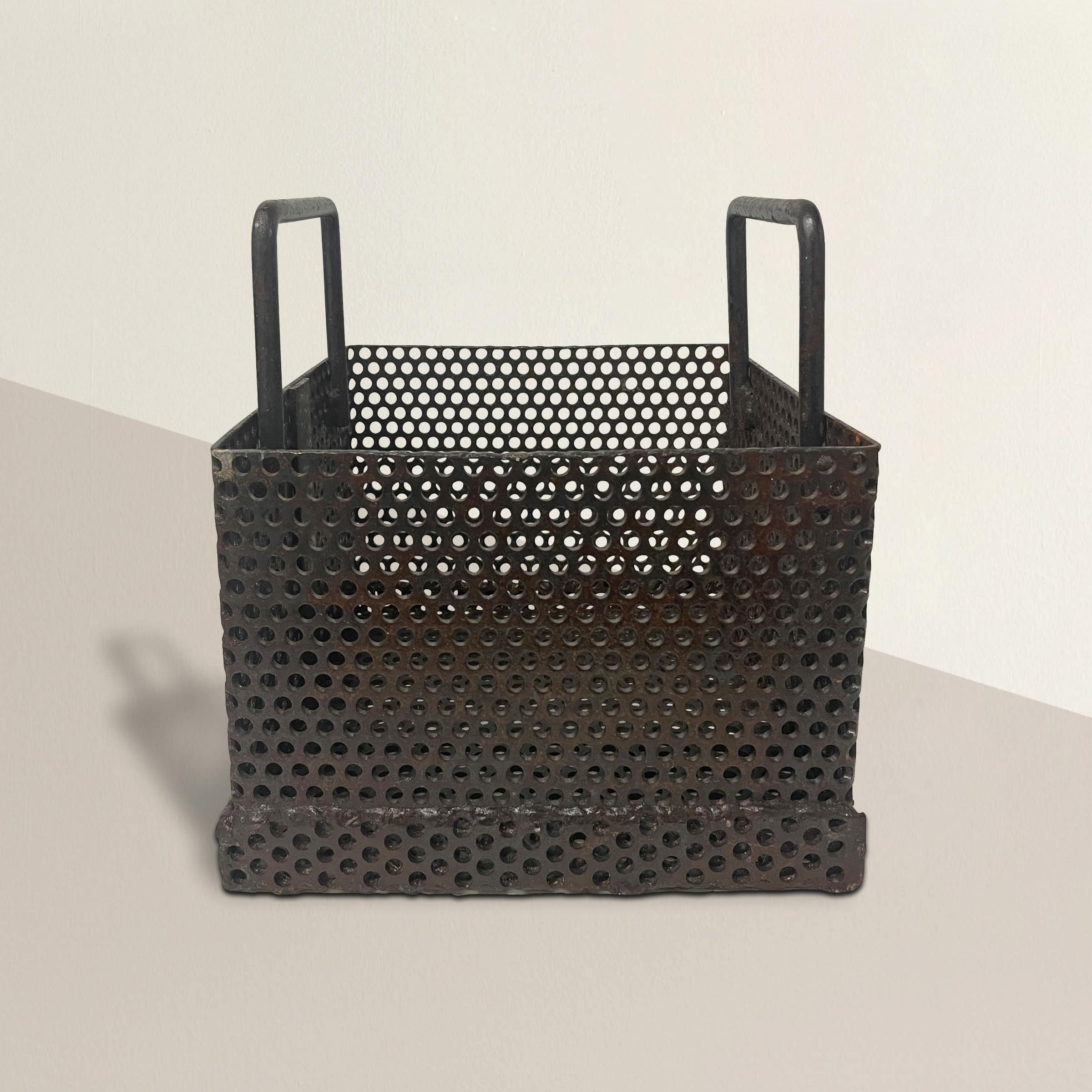 An incredible early 20th century American industrial steel basket with pierced sides and two bent steel handles. This basket was probably used to filter something, with the holes allowing water to pass freely, but today it's the perfect small
