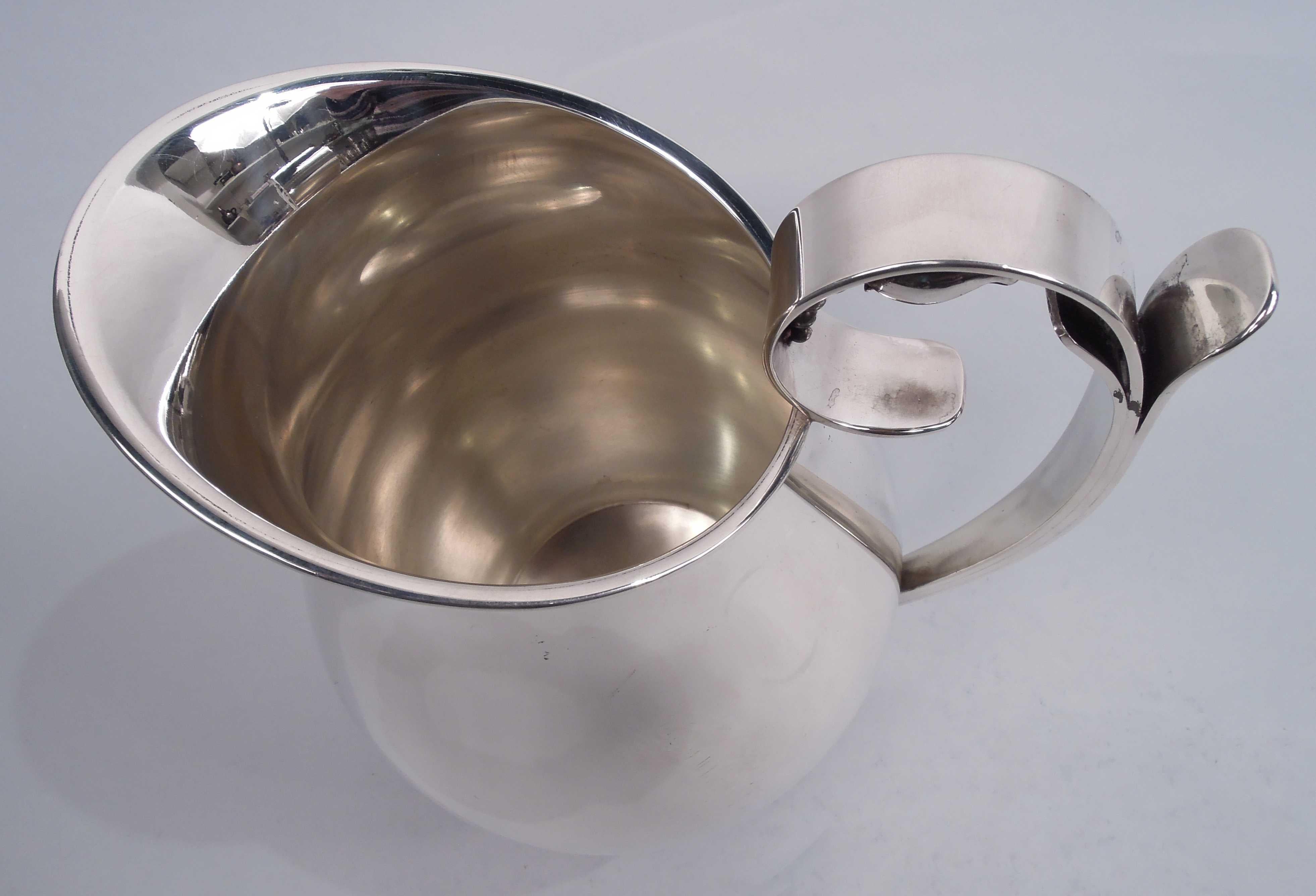 Midcentury Modern sterling silver water pitcher. Made by Alphonse La Paglia (d. 1953) in New Jersey. Baluster with asymmetrical oval mouth; stepped and round foot ring with flat beading. High-looping handle wrapped with abstract leaves; scroll