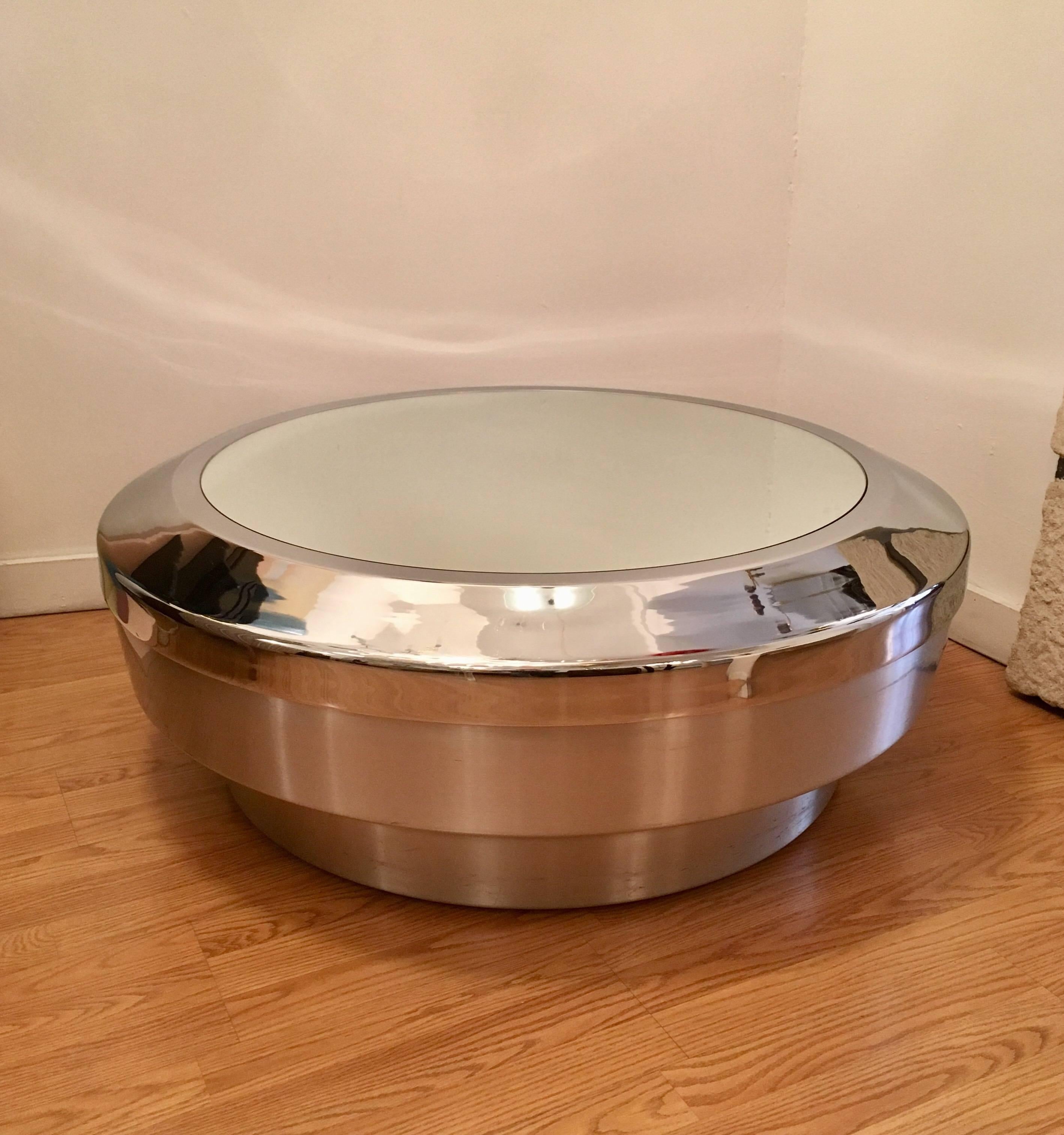 A sleek modern American 1960s coffee table designed by John Neville. The table is composed of a brushed silver metal base with a polished chrome rim top and a mirror glass.