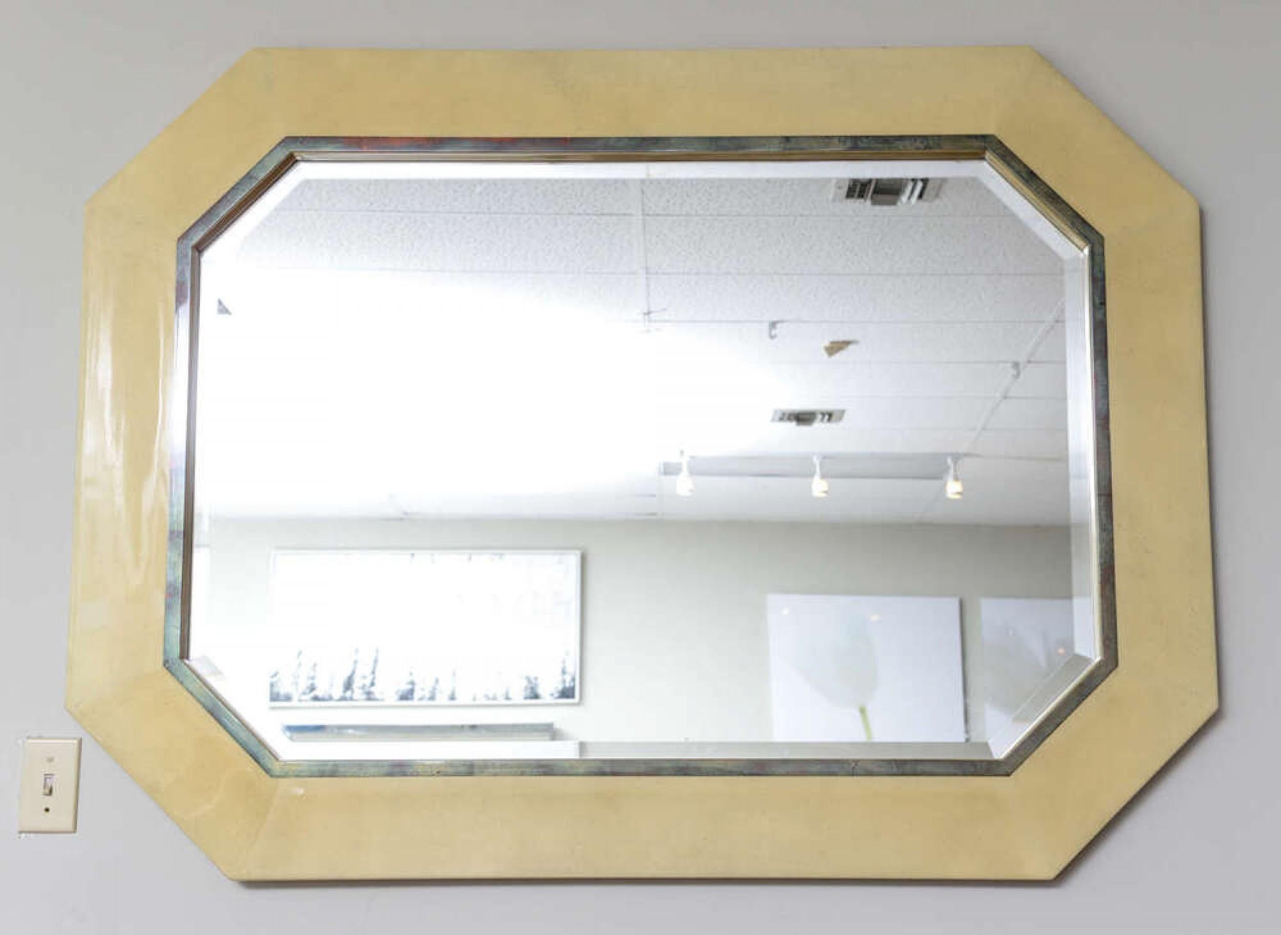 Midcentury American wall mirror with an octagonal frame finished with a beige parchment and lacquer veneer. (in the style of Karl Springer).