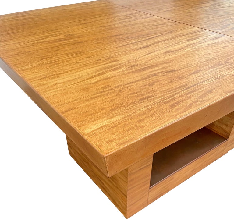 An exceptional American Machine Age extendable dining table. Beautiful, minimalist rectilinear design with thick, reverse-bevel table top on an open base with copper detail. Striking, densely-figured, honey-colored woodgrain veneer throughout. Table
