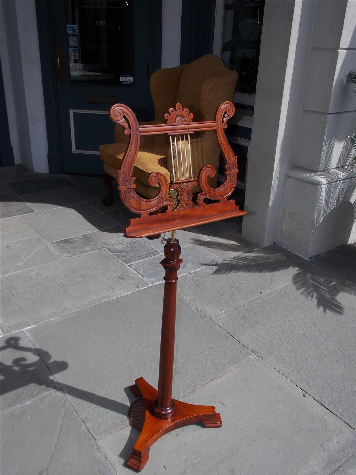 American mahogany and brass music stand with a floral lyre rack shelf, decorative telescopic tilting shaft, turned bulbous centered column, and resting on a tripod base with step back squared feet. Late 19th century. Stamped by maker Palmer, NY.