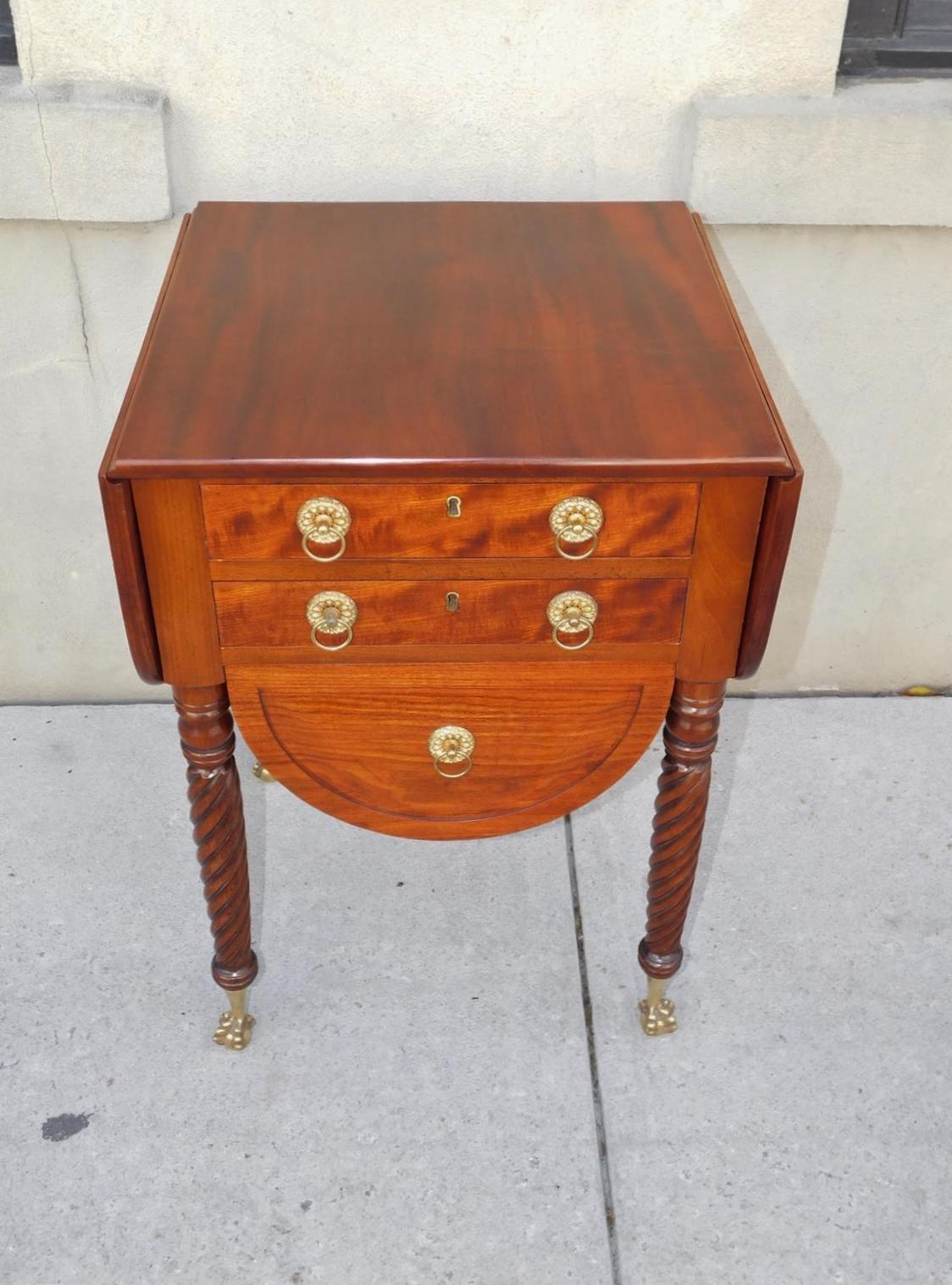 American Federal Mahogany drop leaf three drawer work table with incised carvings, original circular foliage brasses, key hole escutcheons, and resting on bulbous ringed barley twist legs with the original tapered brass claw and ball feet, Early