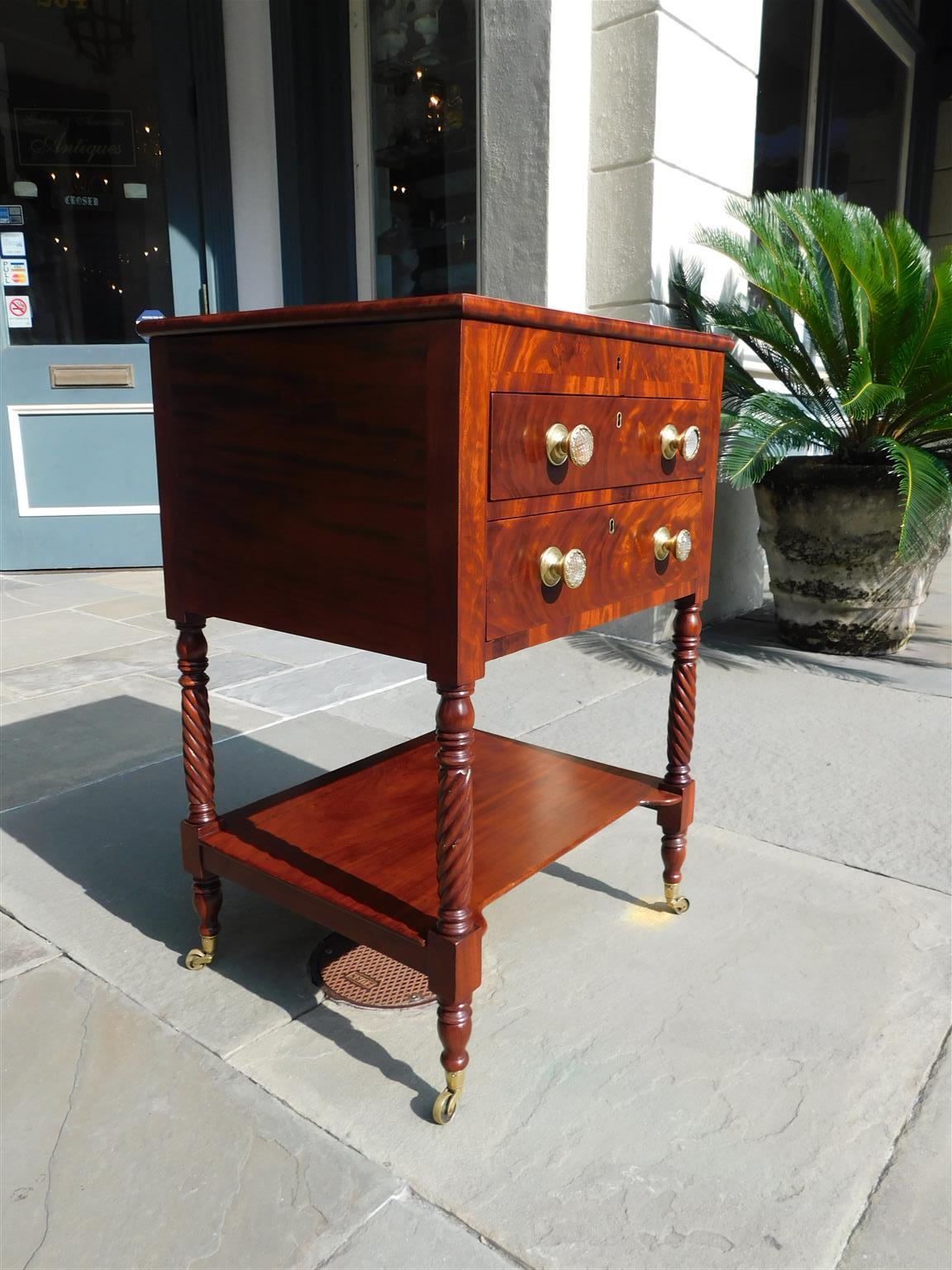 American mahogany Federal two drawer hinged work table with a ratcheted white pine writing surface, fitted interior for ink wells, original brass sandwich glass knobs, lower connecting shelf, and resting on turned bulbous barley twist legs with the