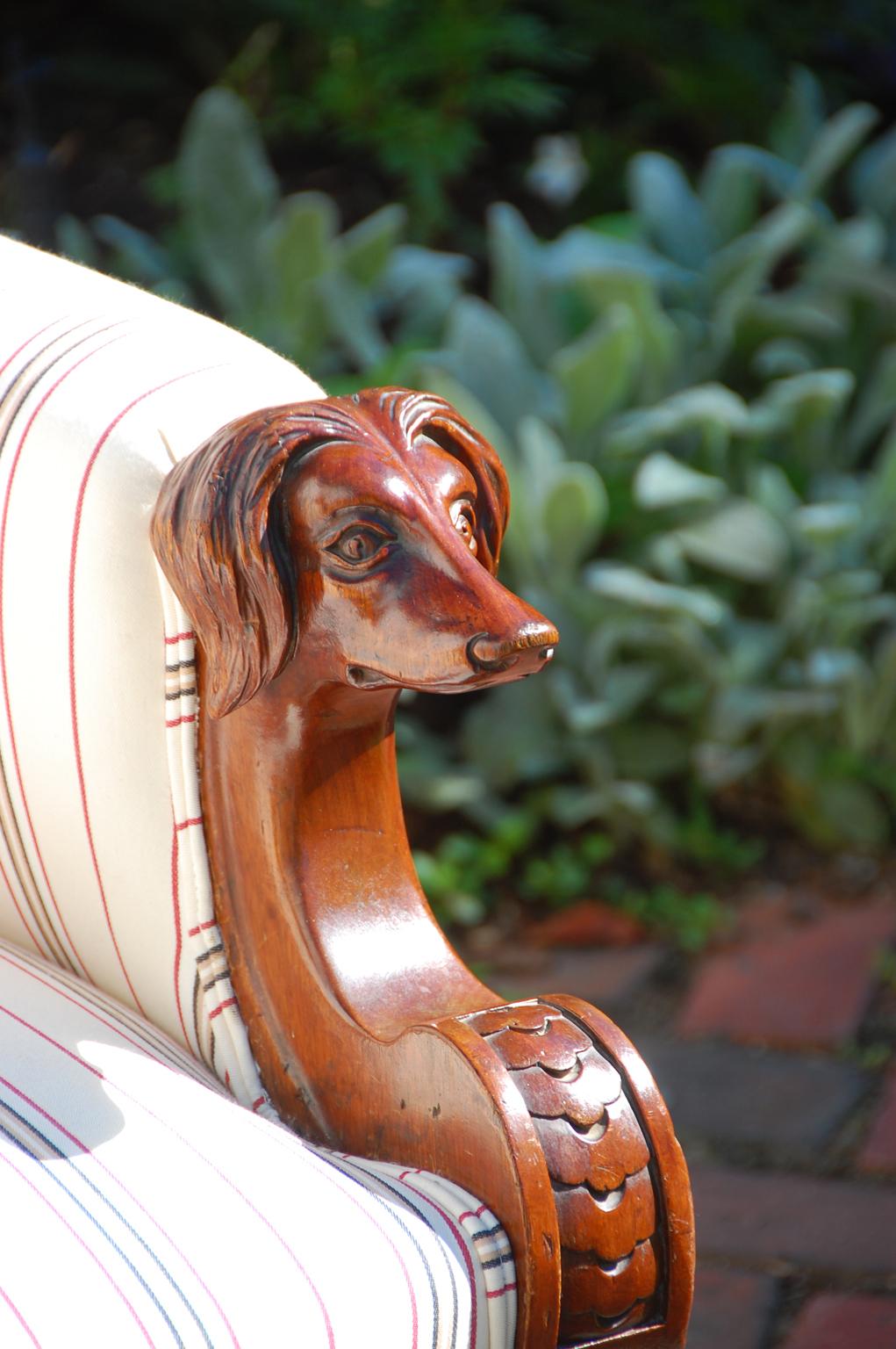 American scroll back lounging chair with hand carved mahogany dog head armrests, turned and carved legs. Probably New York Origin, circa 1875. Newly upholstered, extremely comfortable, circa 1875.