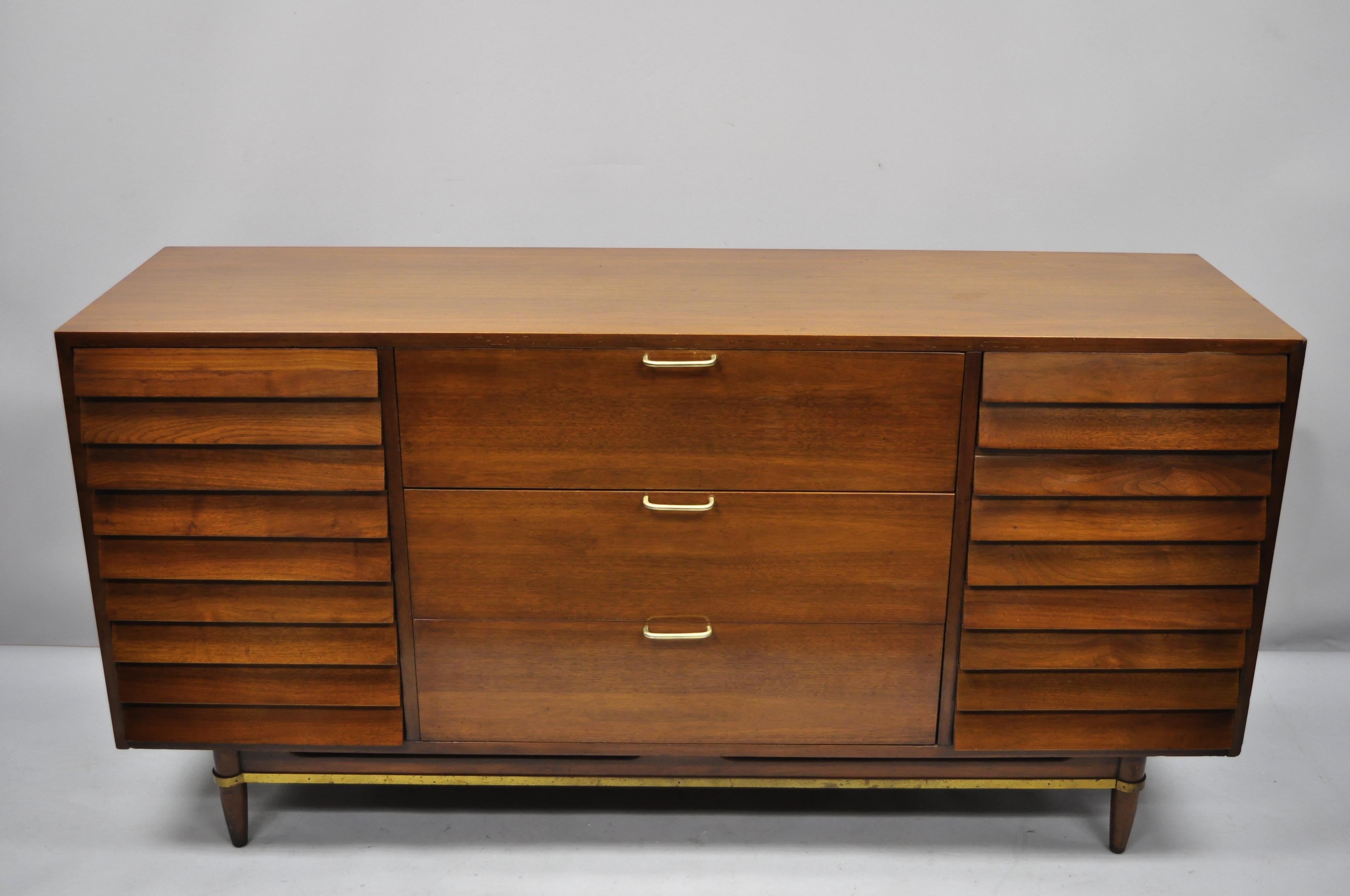 American of Martinsville Walnut 9 Louvered Drawer Mid Century Modern Dresser Credenza. Item features louvered drawers, brass stretcher, beautiful wood grain, original stamp, 9 dovetailed drawers, tapered legs, clean modernist lines, great style and