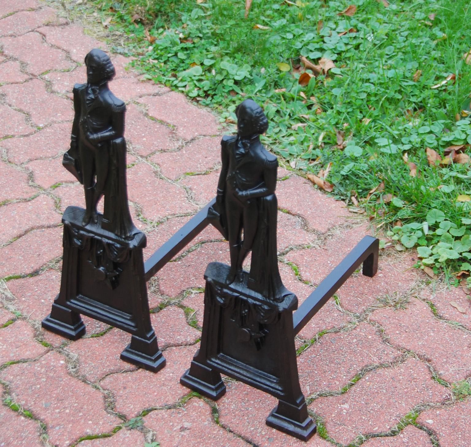 American cast iron George Washington andirons of the mid 19th century. These large scale andirons depict George Washington relaxing in his military dress uniform, leaning against a draped pillar, casually holding his hat in his right hand. He is