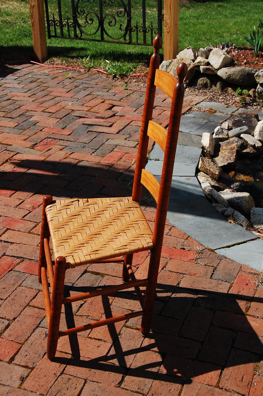 American curly maple Shaker ladderback side chair with woven splint seat and tilters to the back legs. The back leg tilter was an invention of the Shakers that allowed the user to tilt back in the chair without breaking the legs. The tilters were