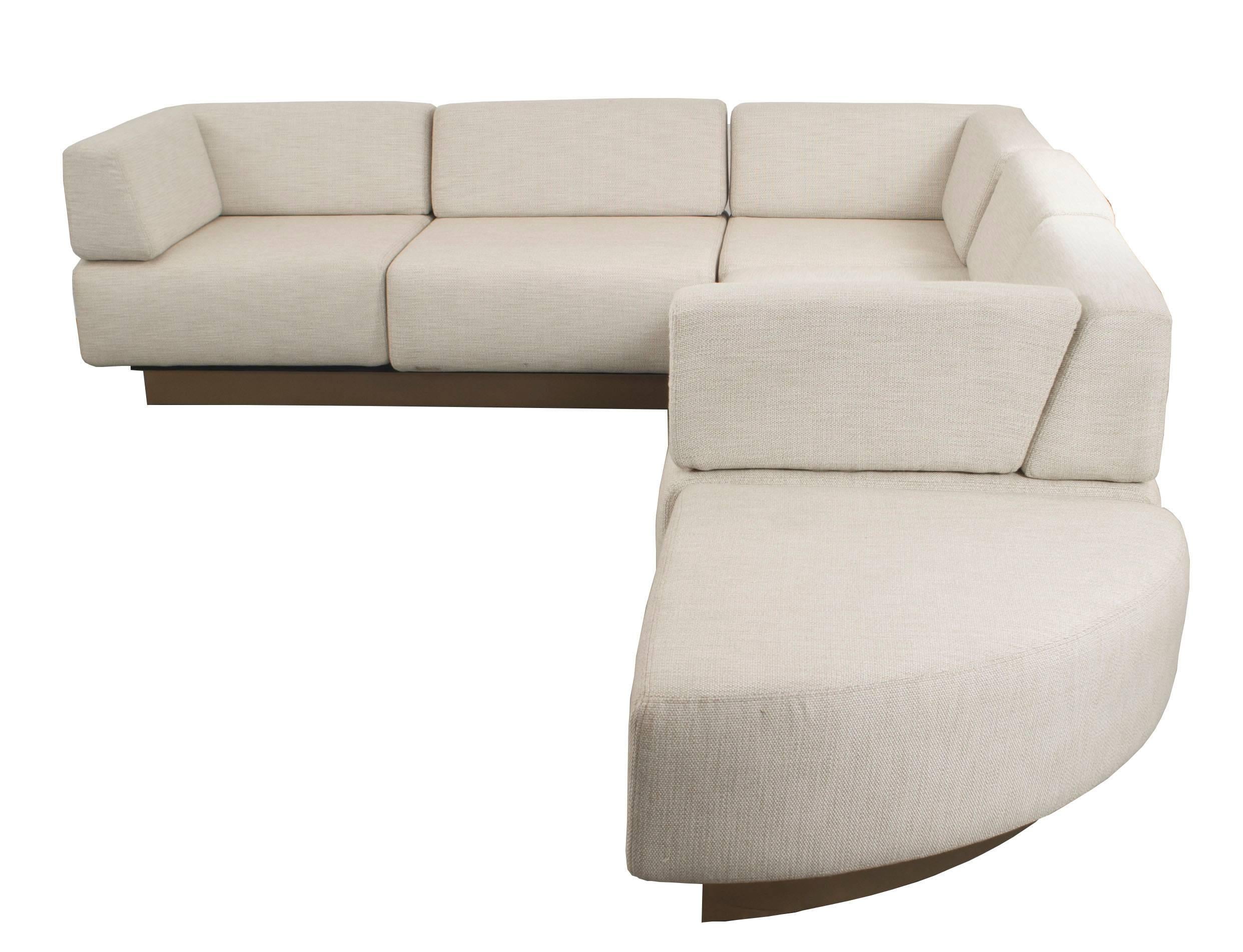 American midcentury four-piece sectional with beige fabric upholstery and a brown wood base frame.  Each arm of sectional: 96