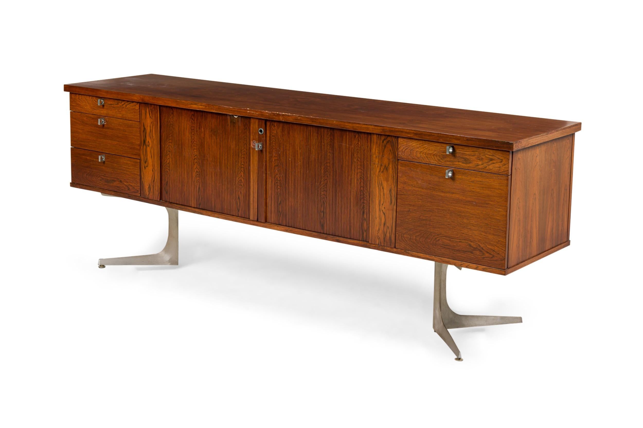 Credenza americana di metà secolo in acero con 5 cassetti e due ante al centro, appoggiata su una coppia di piedistalli in metallo argentato.