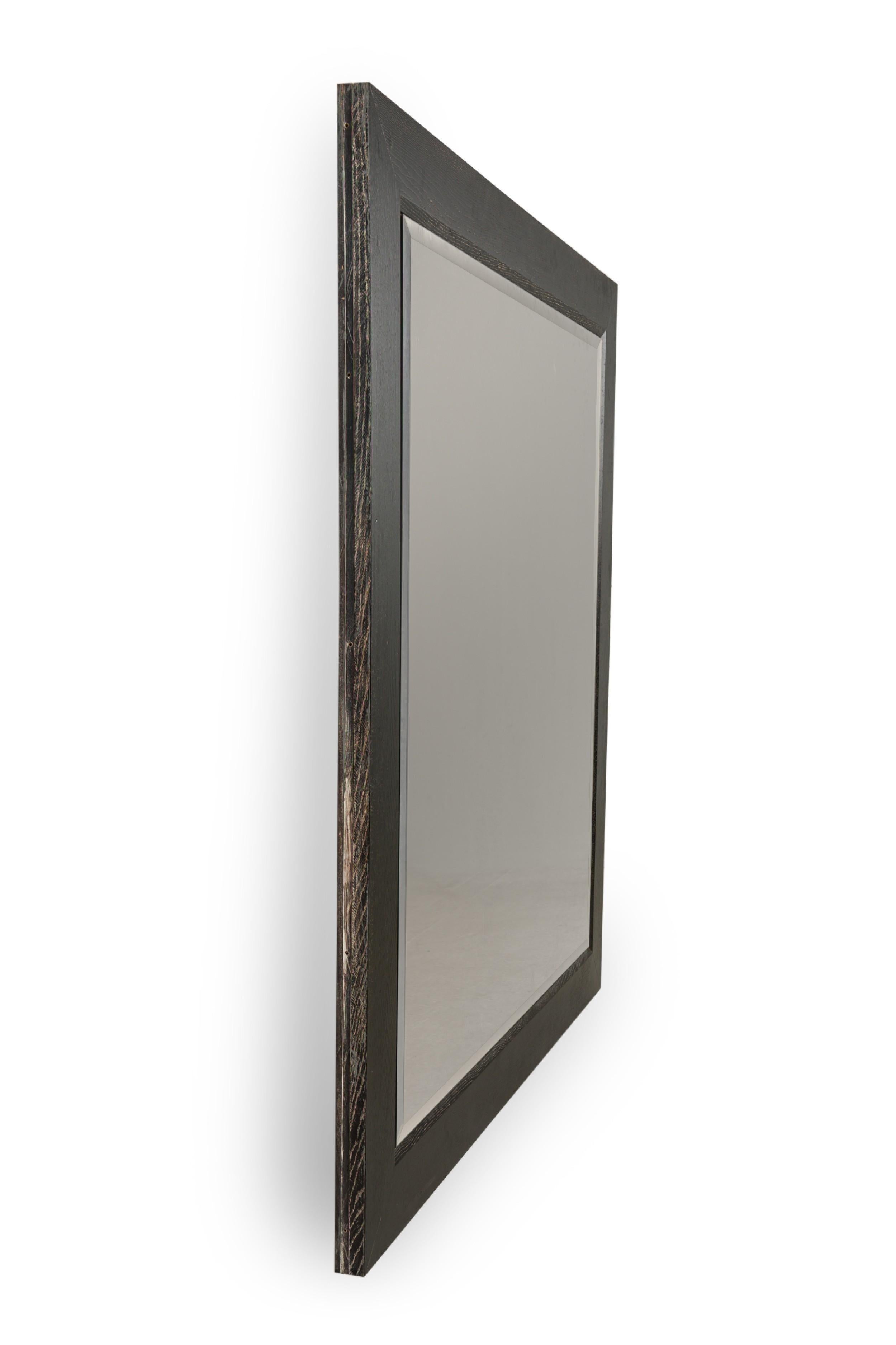 American Mid-Century wall mirror with a ebonized limed oak frame and having a beveled glass (ATT: JAMIE HERZLINGER)

