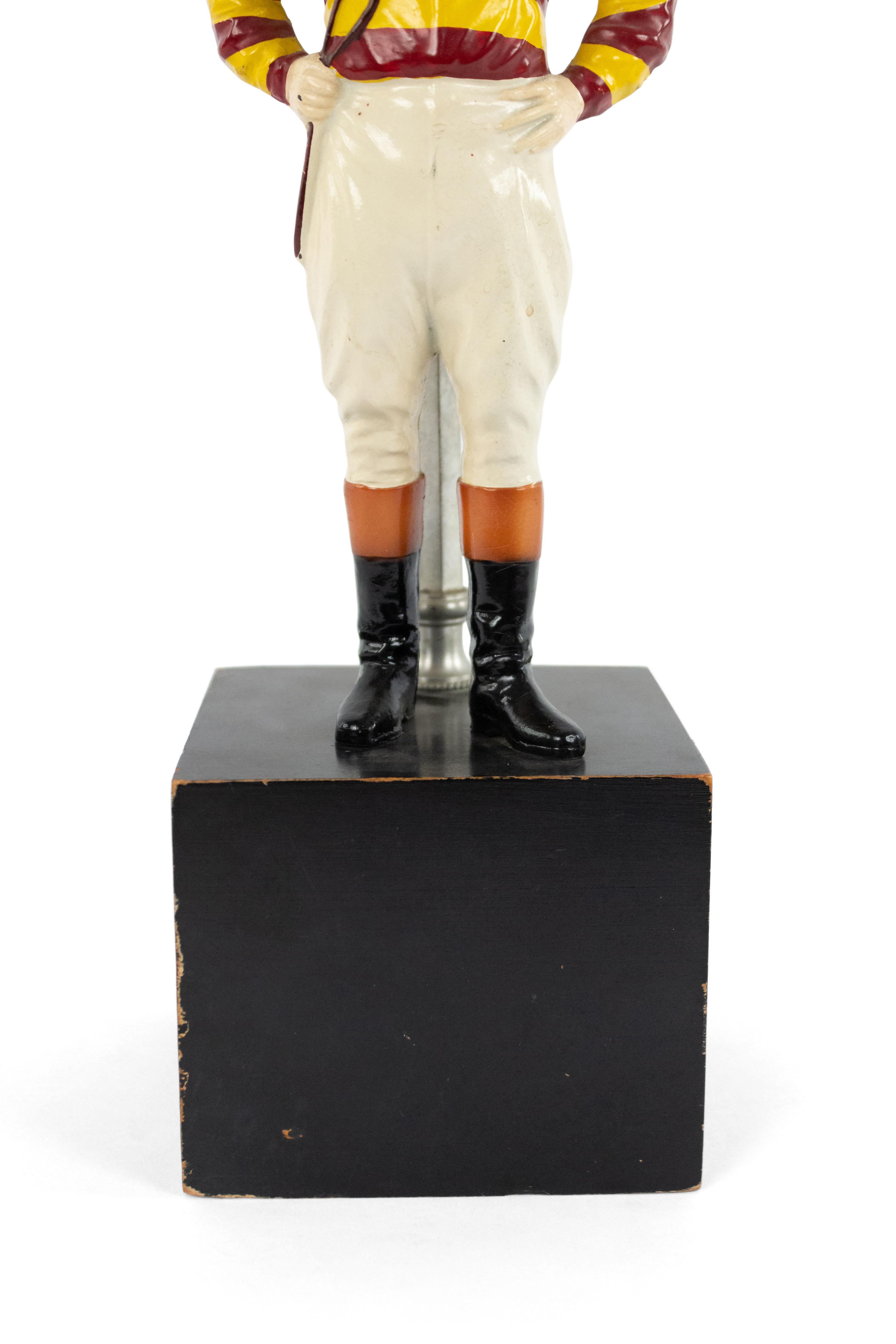 American 1940s painted metal table lamp with jockey figure standing on ebonized square wood base with horseshoe finial.