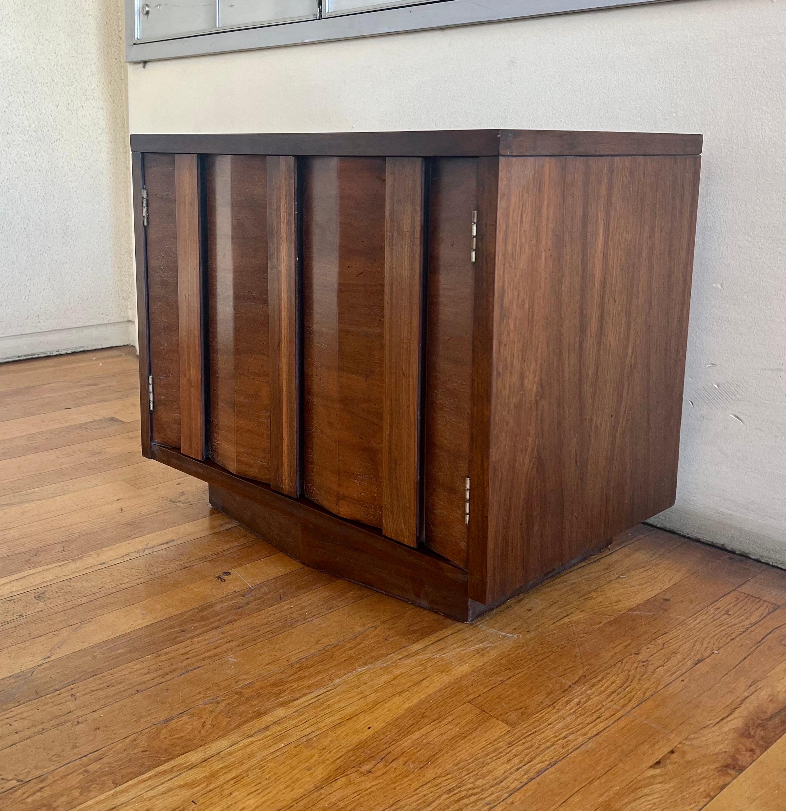 Wonderful pair of midcentury, American walnut nightstands/end tables with geometric doors and great base, circa 1950s. The pair has its original finish very clean we have cleaned and oiled . Very unique angular pieces.