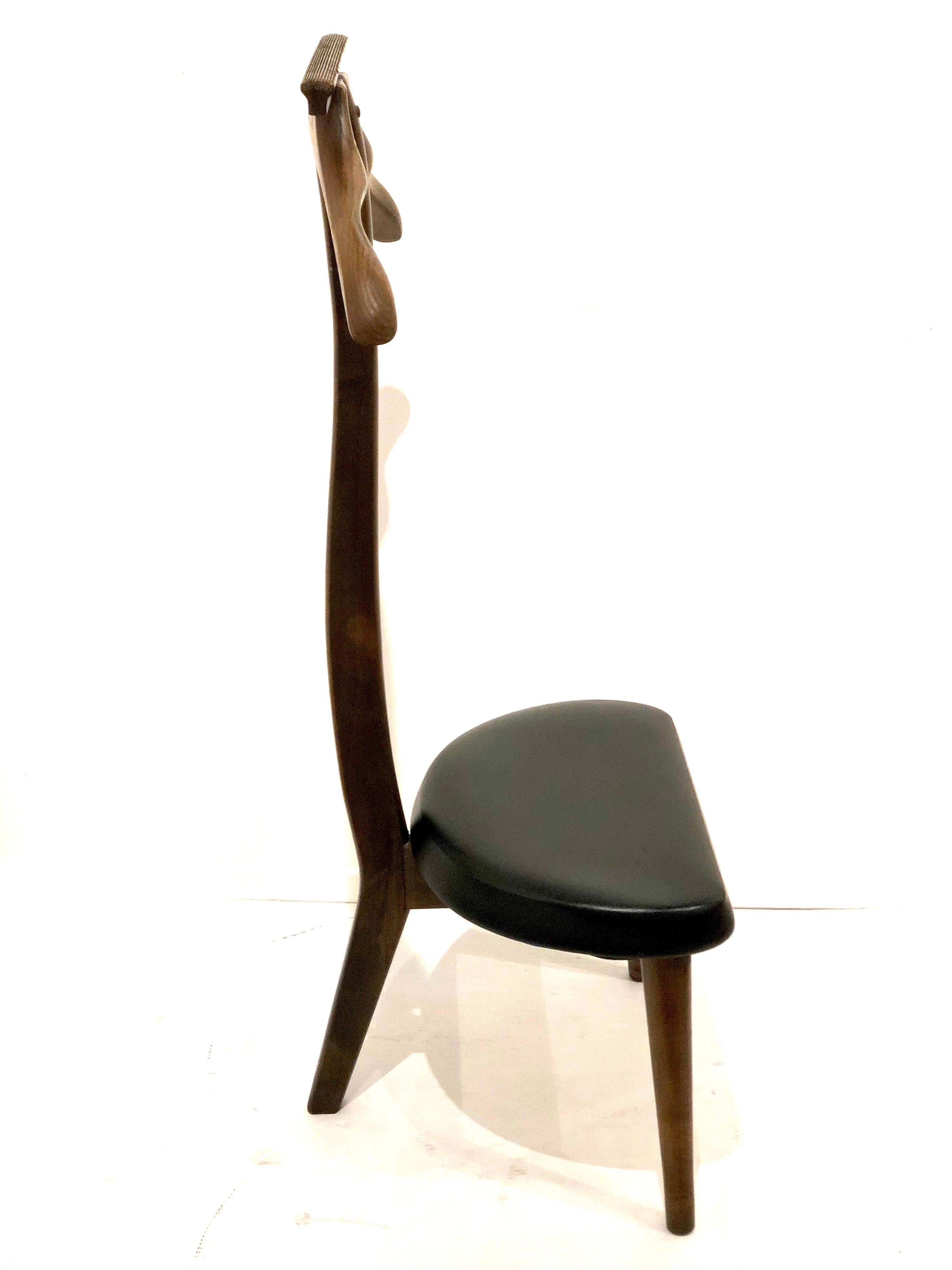 Mid-Century Modern walnut men's valet stand with black Naugahyde, circa 1950s. Simple design with clean leans in original good vintage condition.