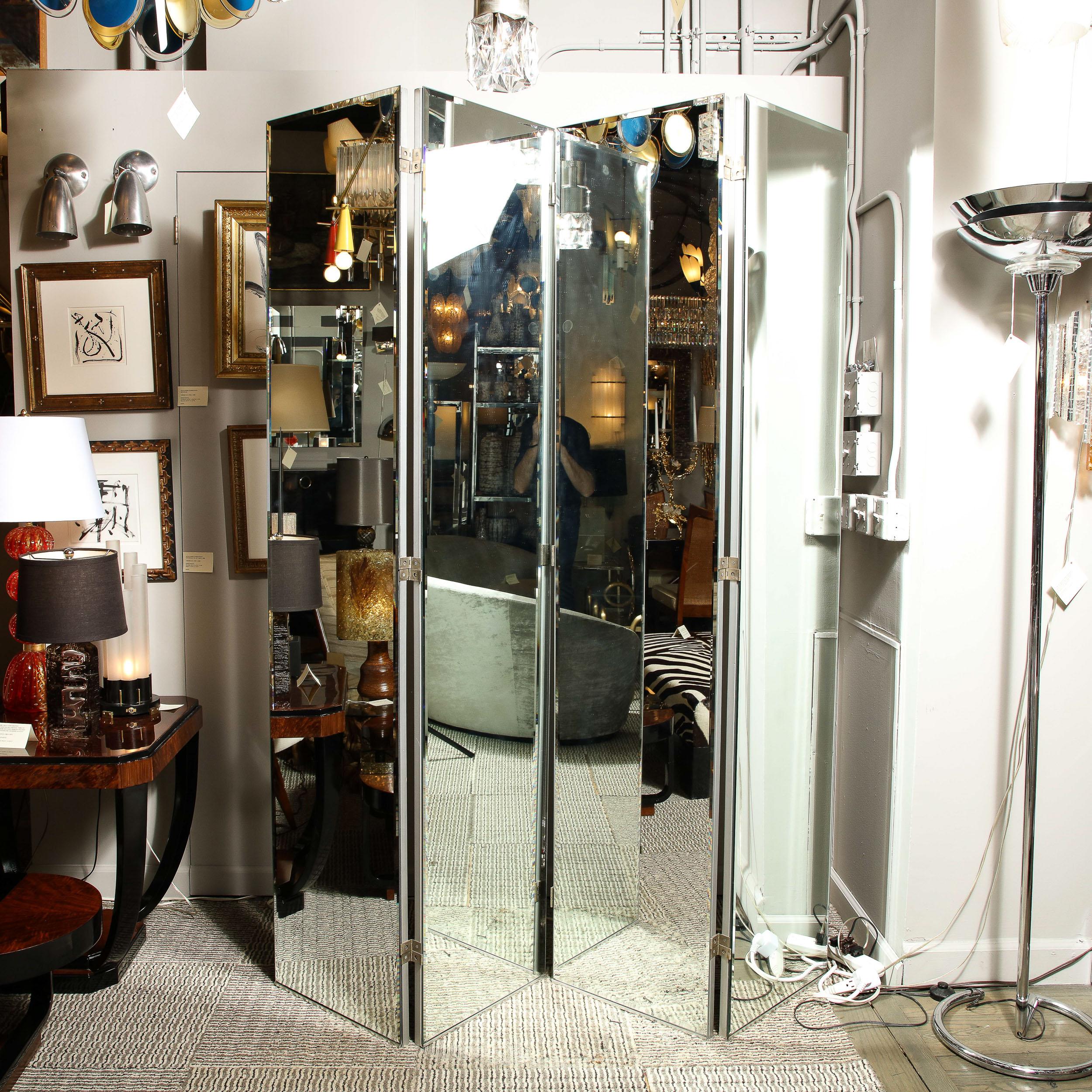 This impressive and monumental four panel Mid-Century Modern mirrored screen was realized in the United States circa 1970. It features four rectangular panels with beveled borders in a pristine clear mirror faceted with silver metal hinges- that