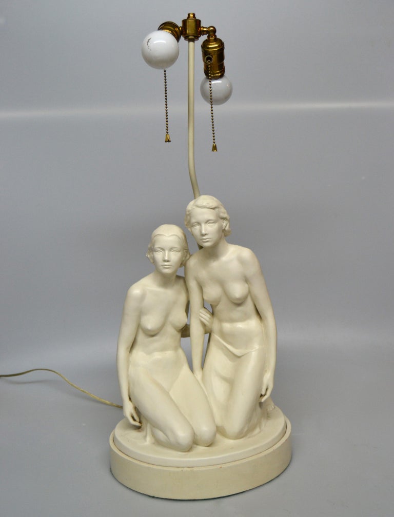 American Mid-Century Modern plaster table lamp features two hand carved nude female and is mounted on a metal base.
The lamp holders are made out of brass with double cluster sockets and pull cords.
Can support two light bulbs of max 60 W each.