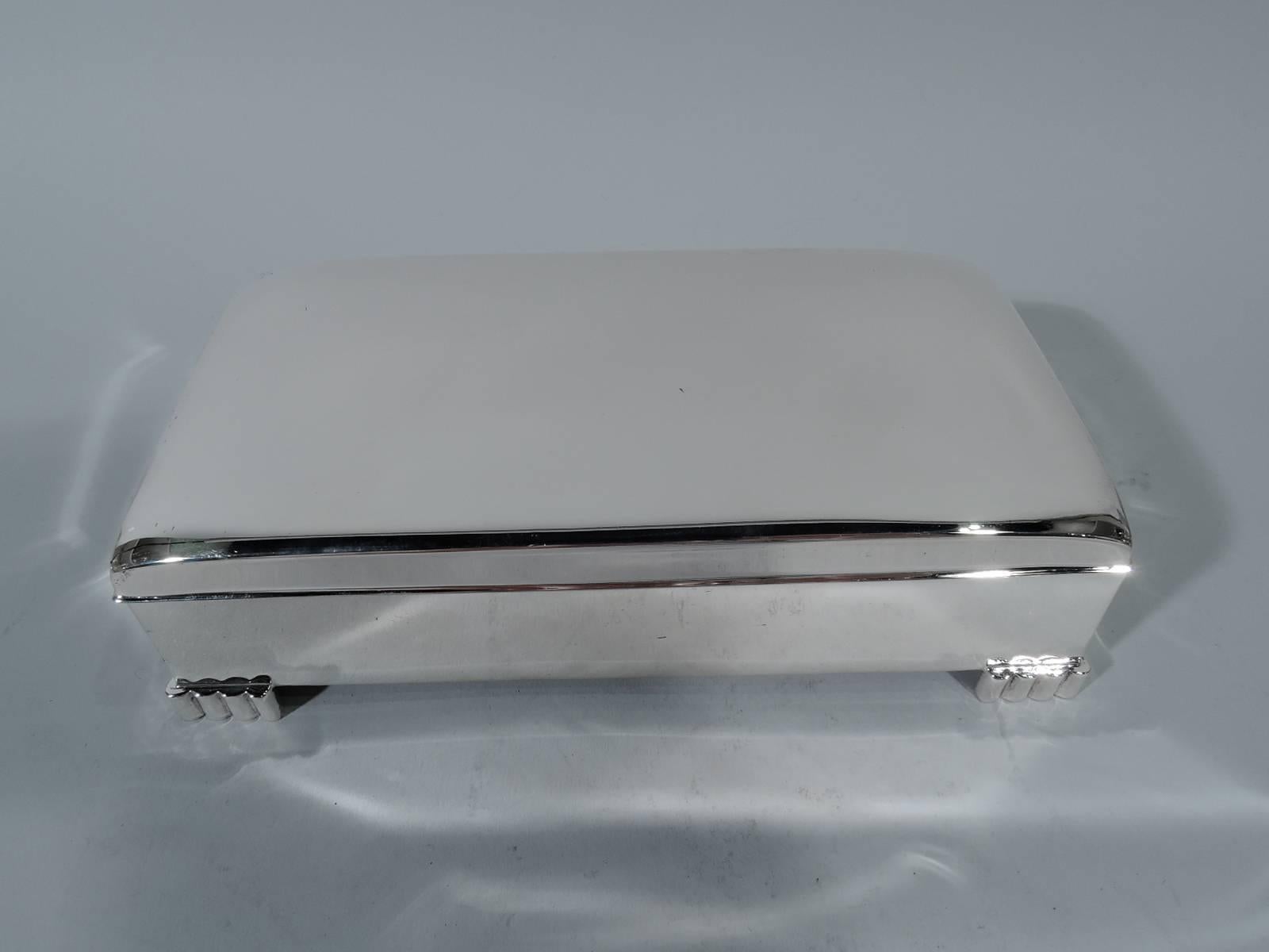 Mid-Century Modern sterling silver box. Made by Poole in Taunton, Mass. Rectangular with straight sides and lobed corner bracket feet. Cover hinged and curved. Box and cover interior cedar lined. Box underside leather lined. Hallmark includes no.