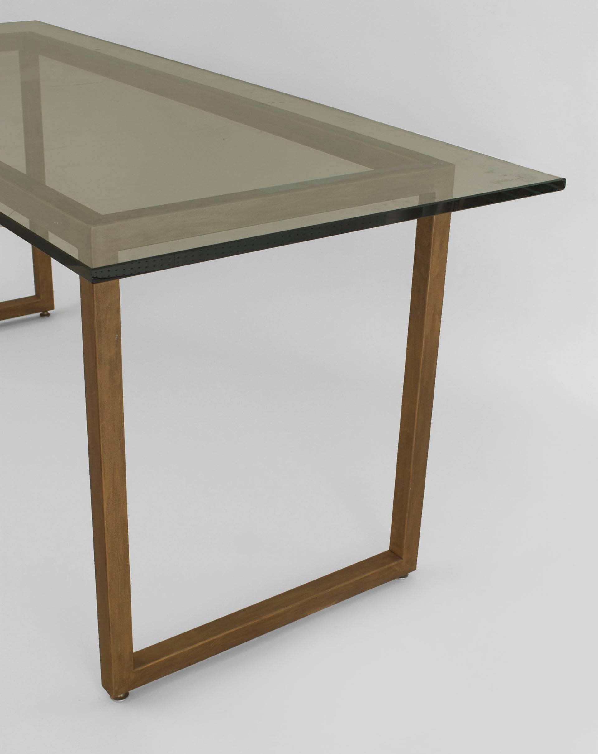 American Mid-Century Modern-style gold painted metal base dining table supporting a large rectangular glass top.
