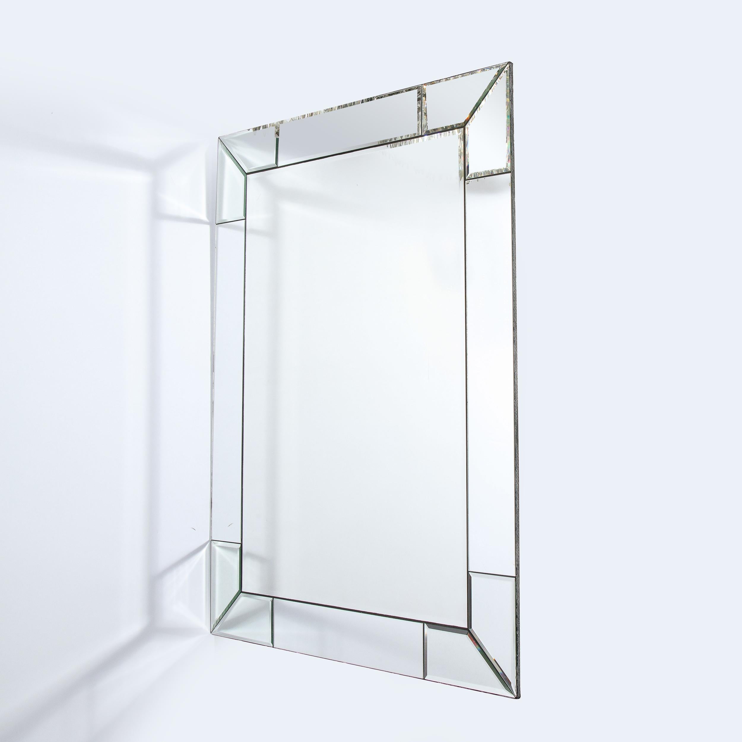 This stunning Custom Modern mirror was realized in the United States, 21st Century. It features a rectangular form with a tessellated border composed of rectilinear mirrored segments with beveled edges that wrap around the perimeter of the piece.