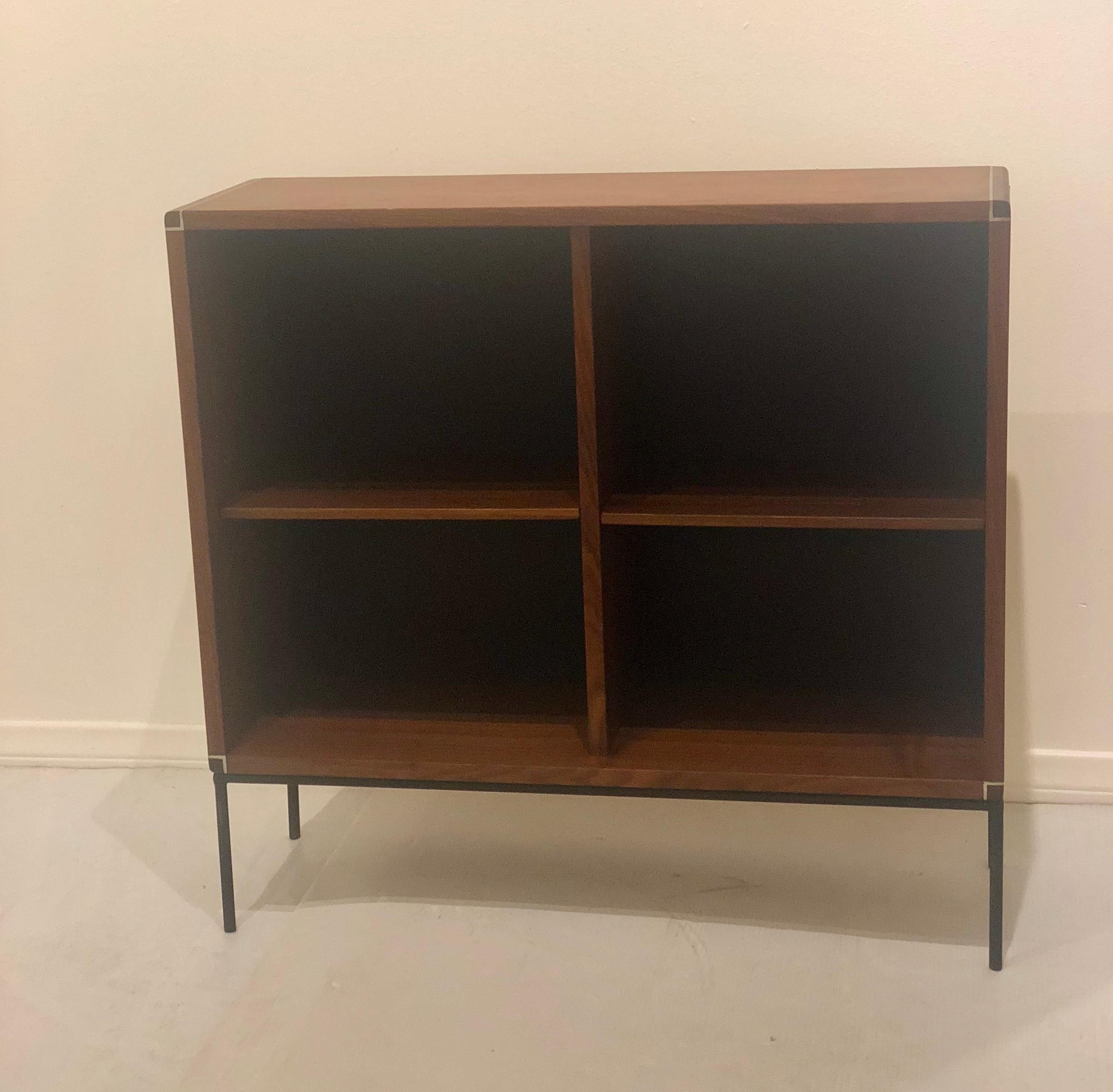 A petit American Mid-Century Modern walnut and iron bookcase. Black backing and polished aluminum accent strips. Has two removable shelves. Freshly refinished case and resprayed the base in black, circa 1960s.