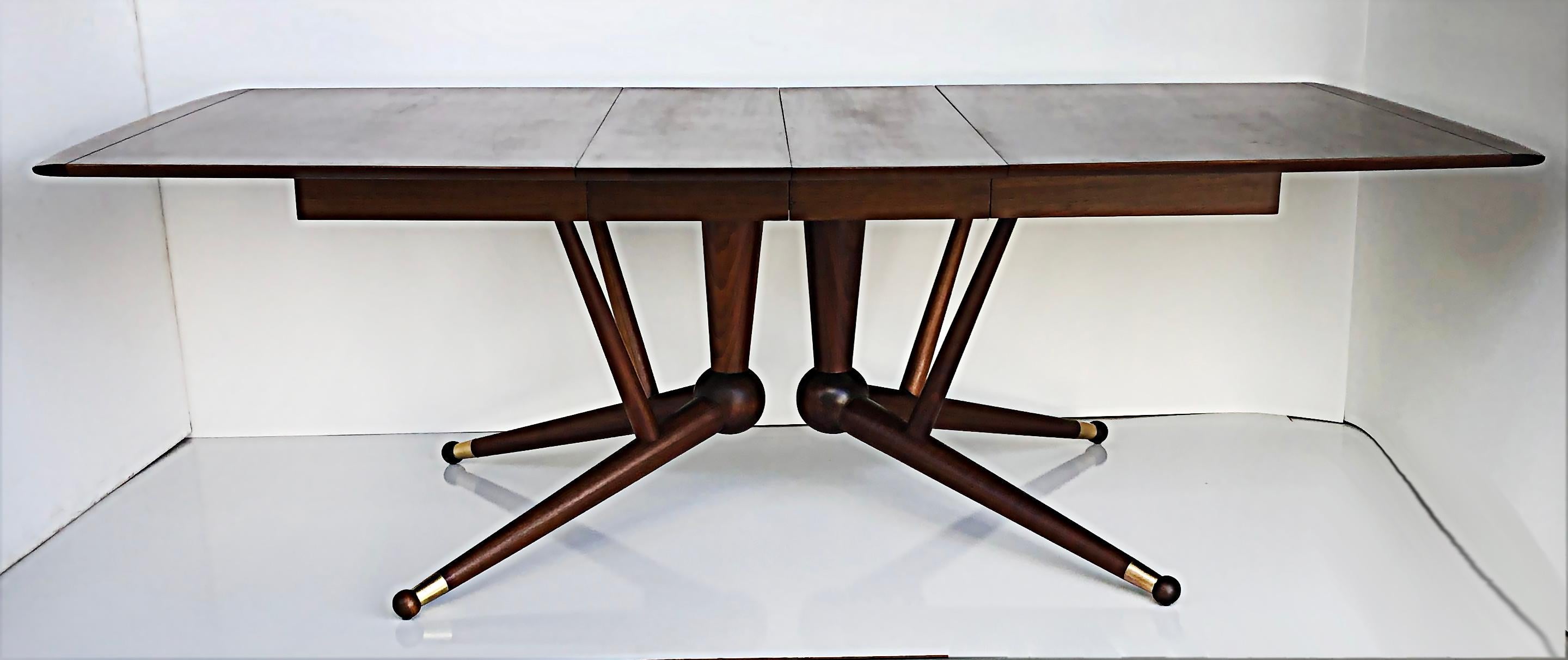American Mid-century Modernist Expandable dining table with Two Wood Leaves

Offered for sale is a recently restored American mid-century modern solid wood expandable dining table with two leaves and banded brass wood legs. The width of each leaf