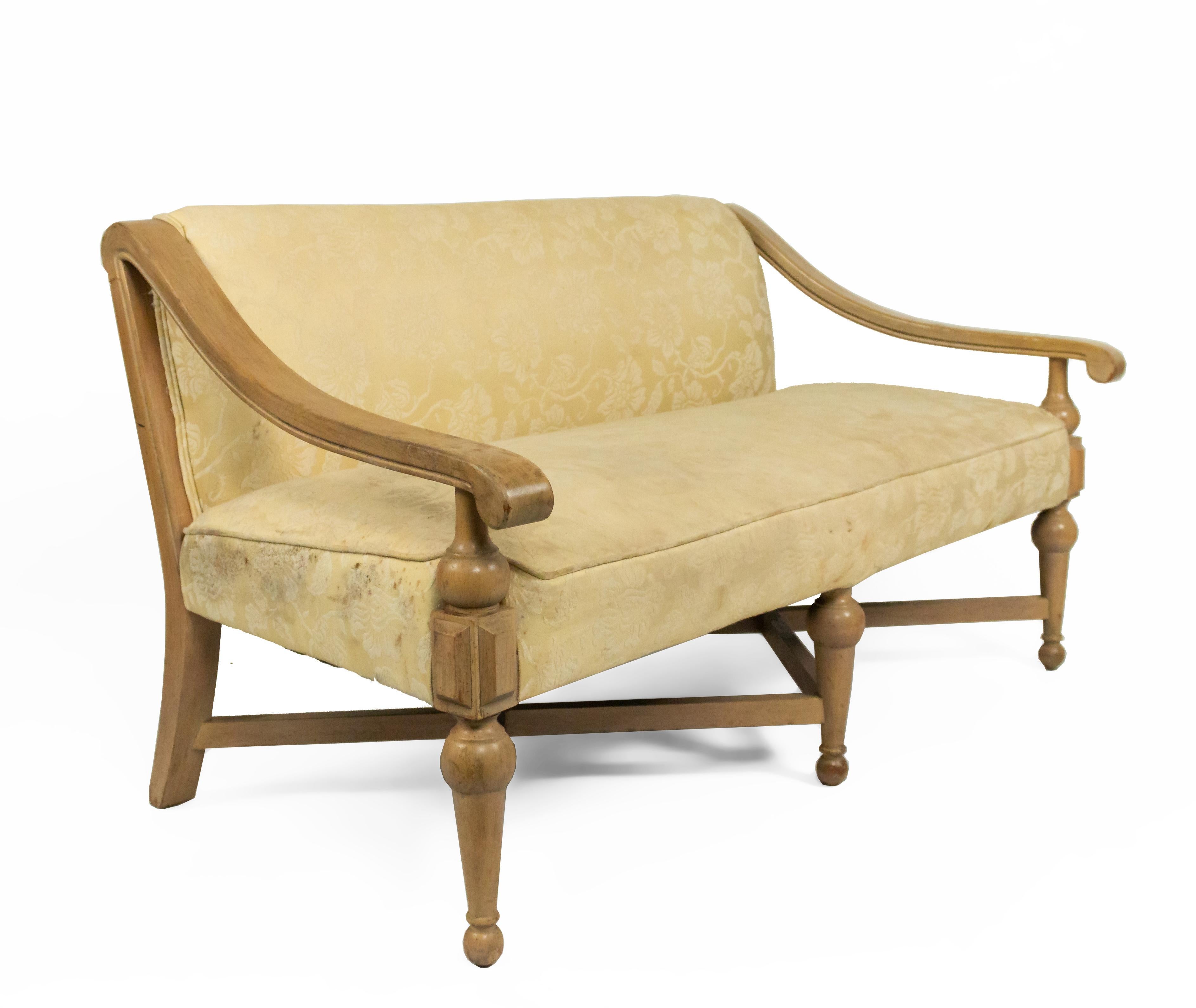 American 1960s sycamore loveseat having a seat and back upholstered in a light yellow floral pattern with an X-stretcher base and back.