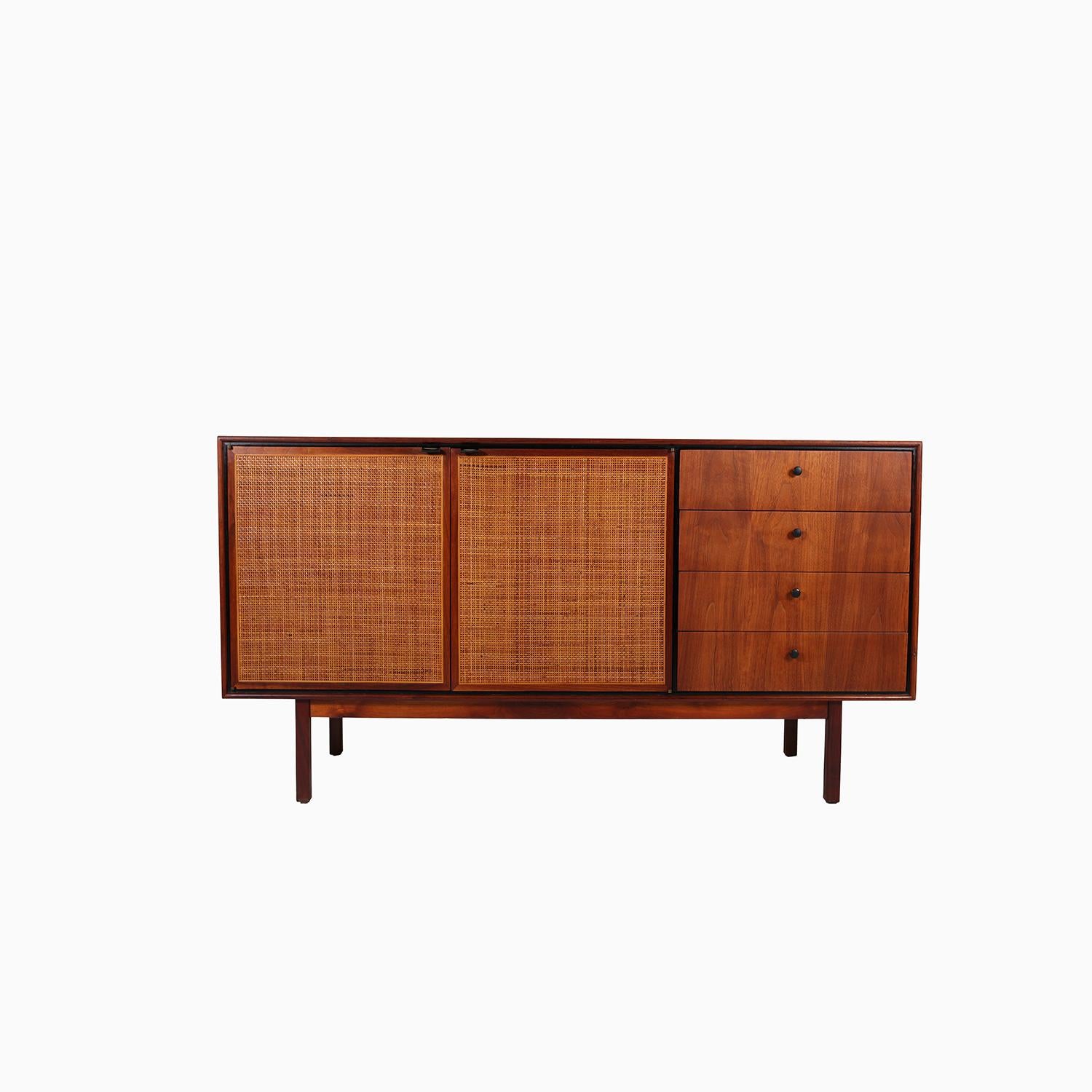 An American Mid-Century Modern sideboard in a rich walnut. Caned front doors, accented by a black trim and black drawer pulls. An attractive sideboard with nice details and features. Ideal as a credenza or for its former intended use as a sideboard