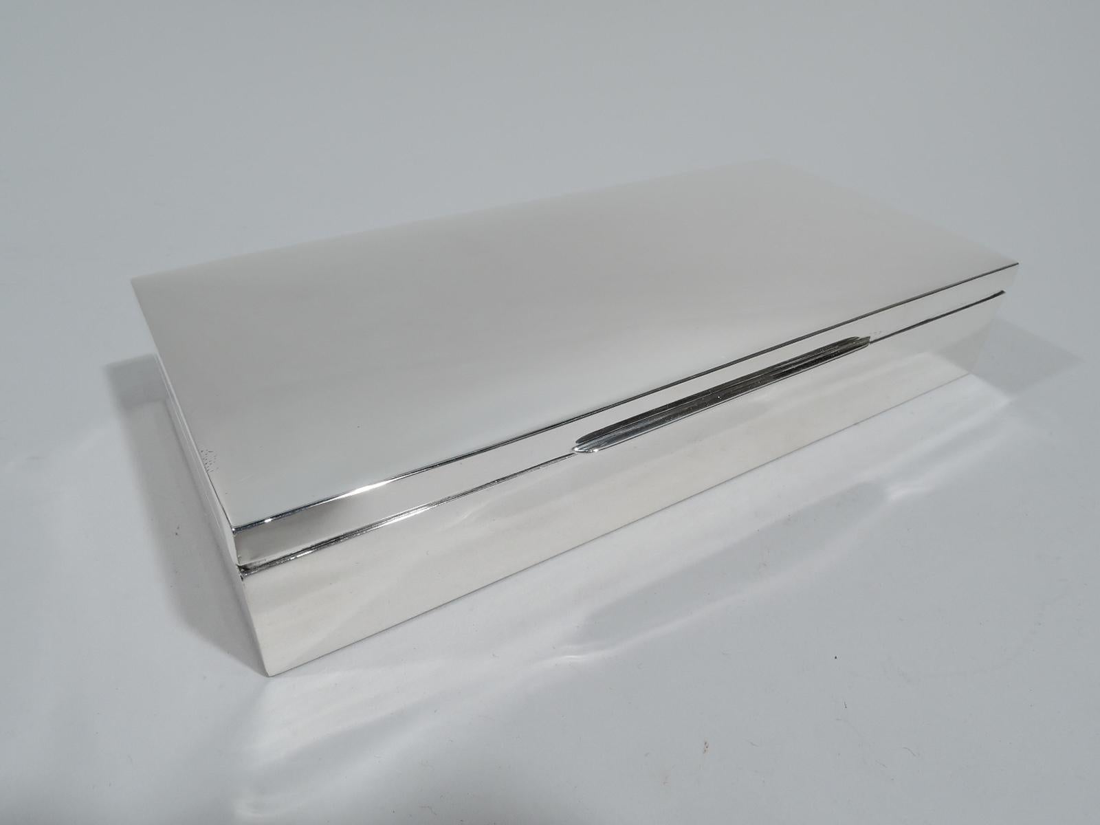 American Mid-Century Modern sterling silver box. Rectangular with straight sides. Cover hinged and gently curved with linear tab. Box interior cedar lined and partitioned. Marked “Sterling”. Gross weight: 12 troy ounces.