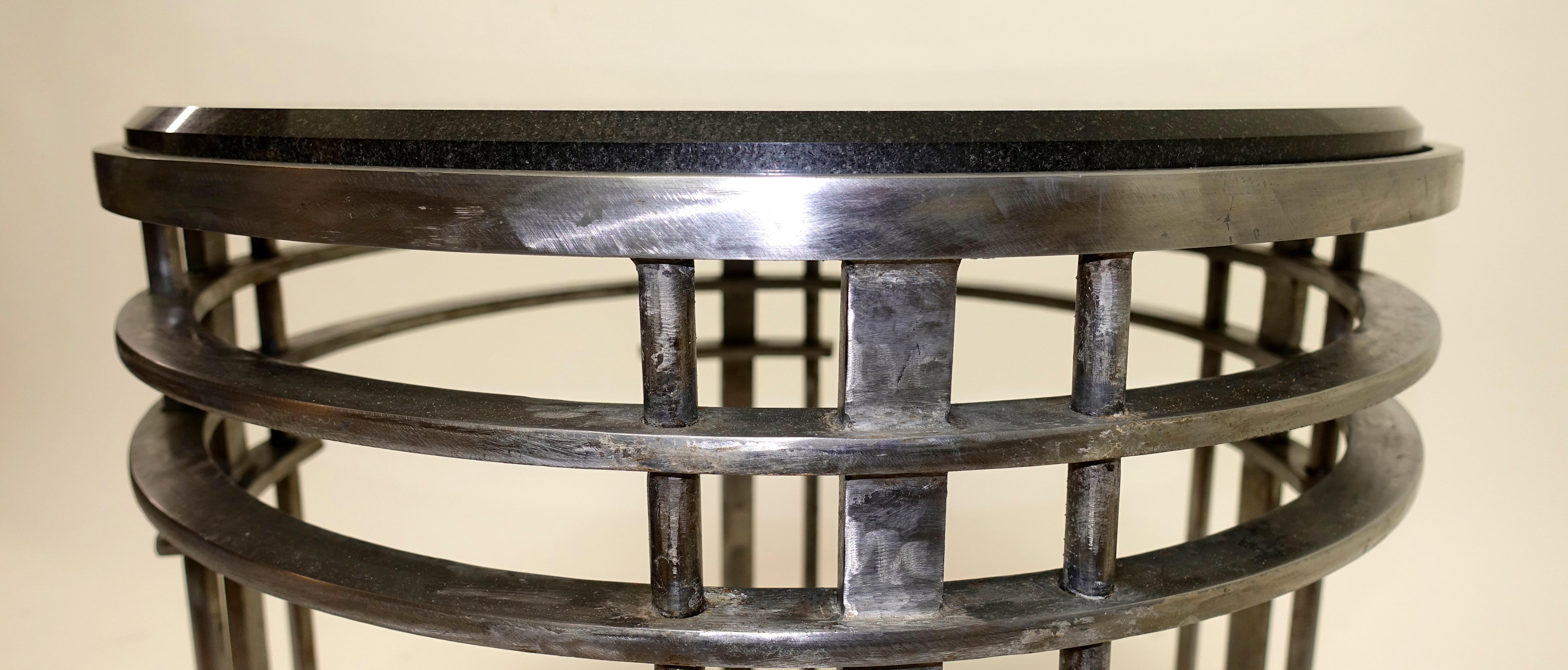 Black beveled granite stone top on a round brushed steel four ring base side or occasional table. 
American 
Mid-20th century.