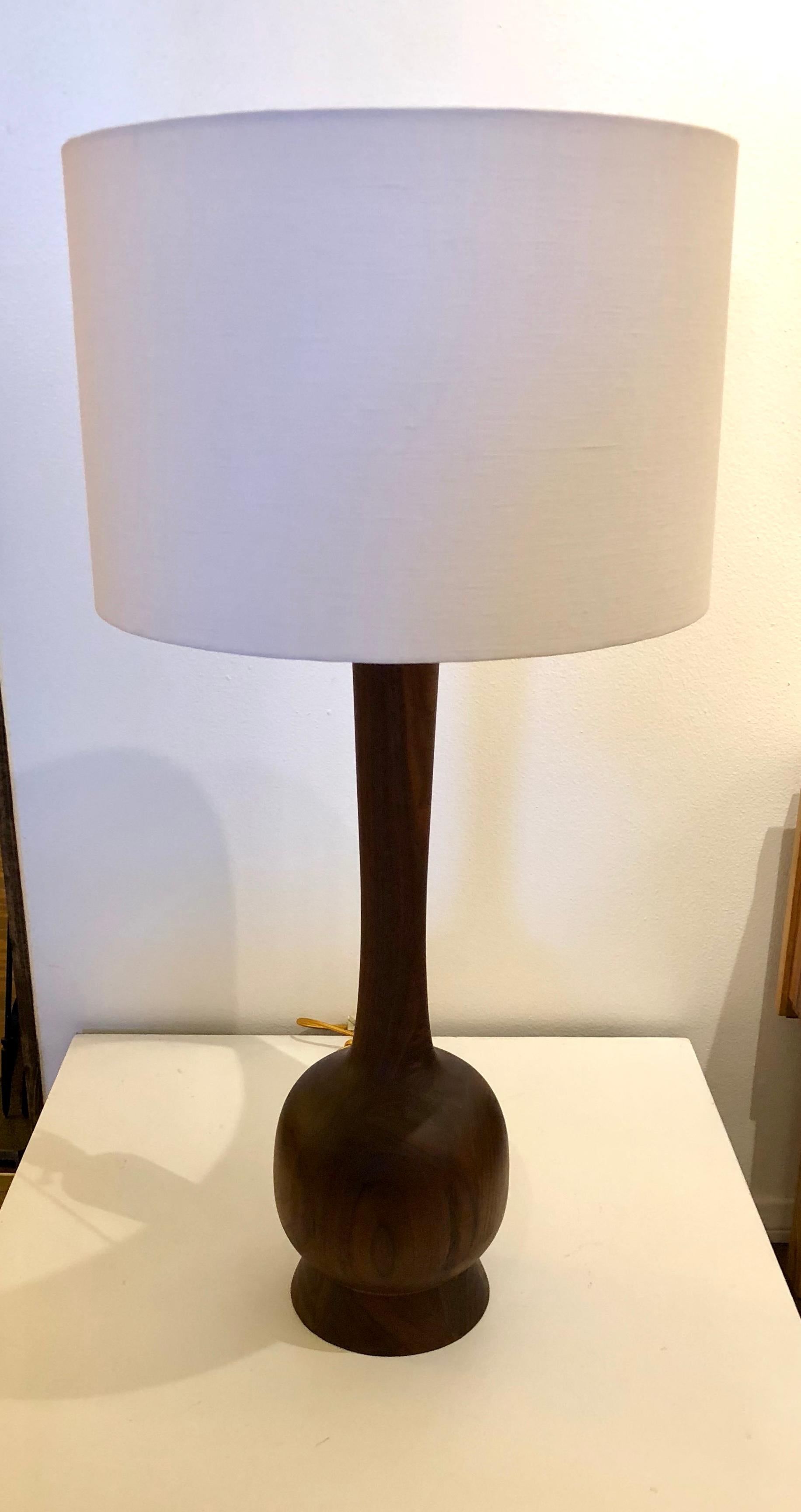 Massive solid walnut pair of tall table lamps, completely restored. This lamps have been refinished, rewired and a pair of new white linen shades, with polished brass fittings and new sockets. Each lamp is 37 1/2