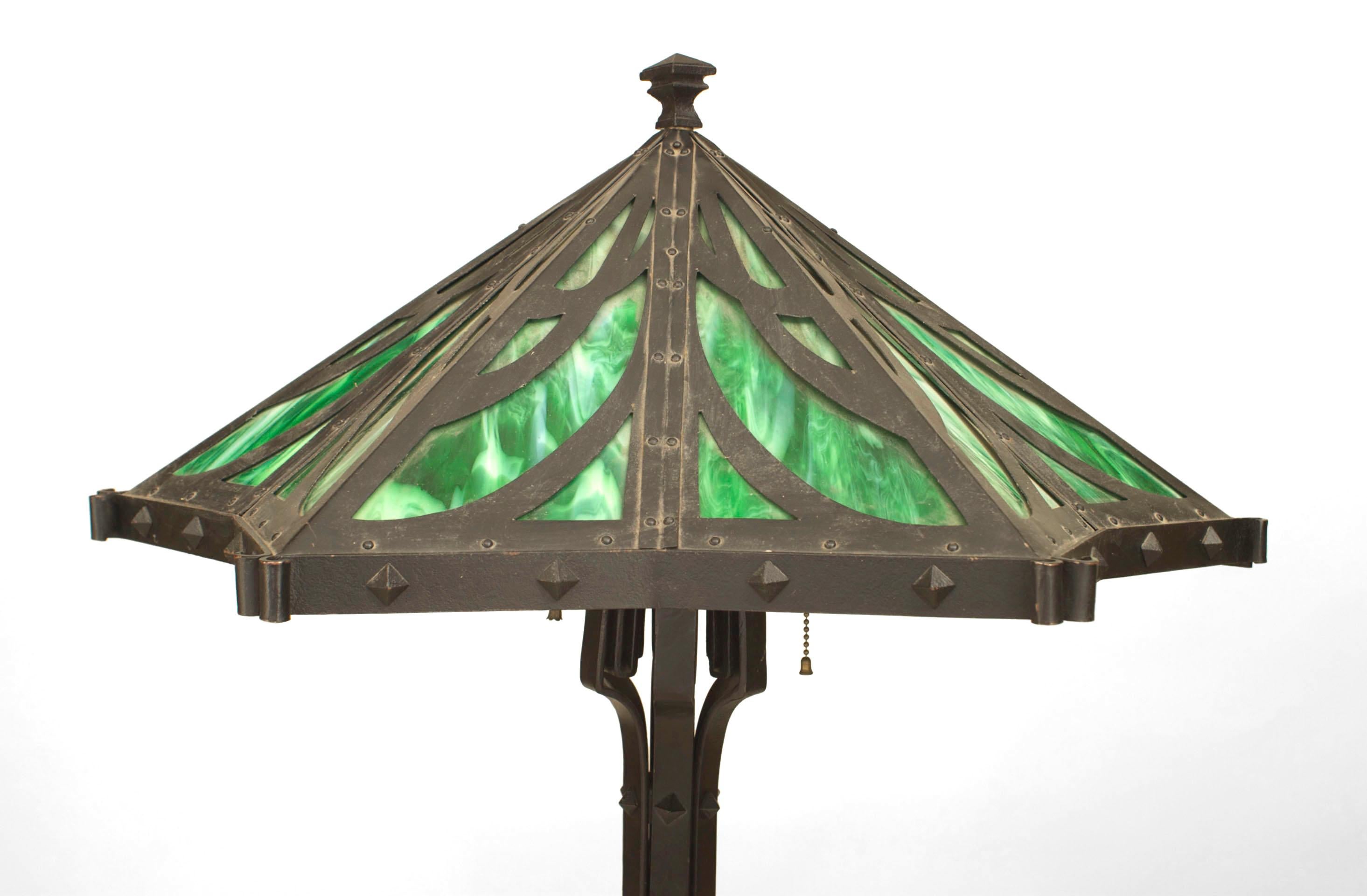 Lampada da tavolo Mission americana in ferro nero con paralume a 6 lati con disegno di vetro verde con scorie sostenuto da 6 volute e rifinito con borchie in metallo.
