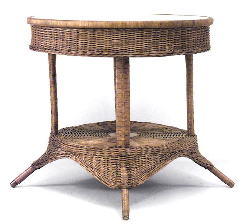American Mission natural wicker round center table with splayed feet and a woven apron and shelf beneath a glass top.