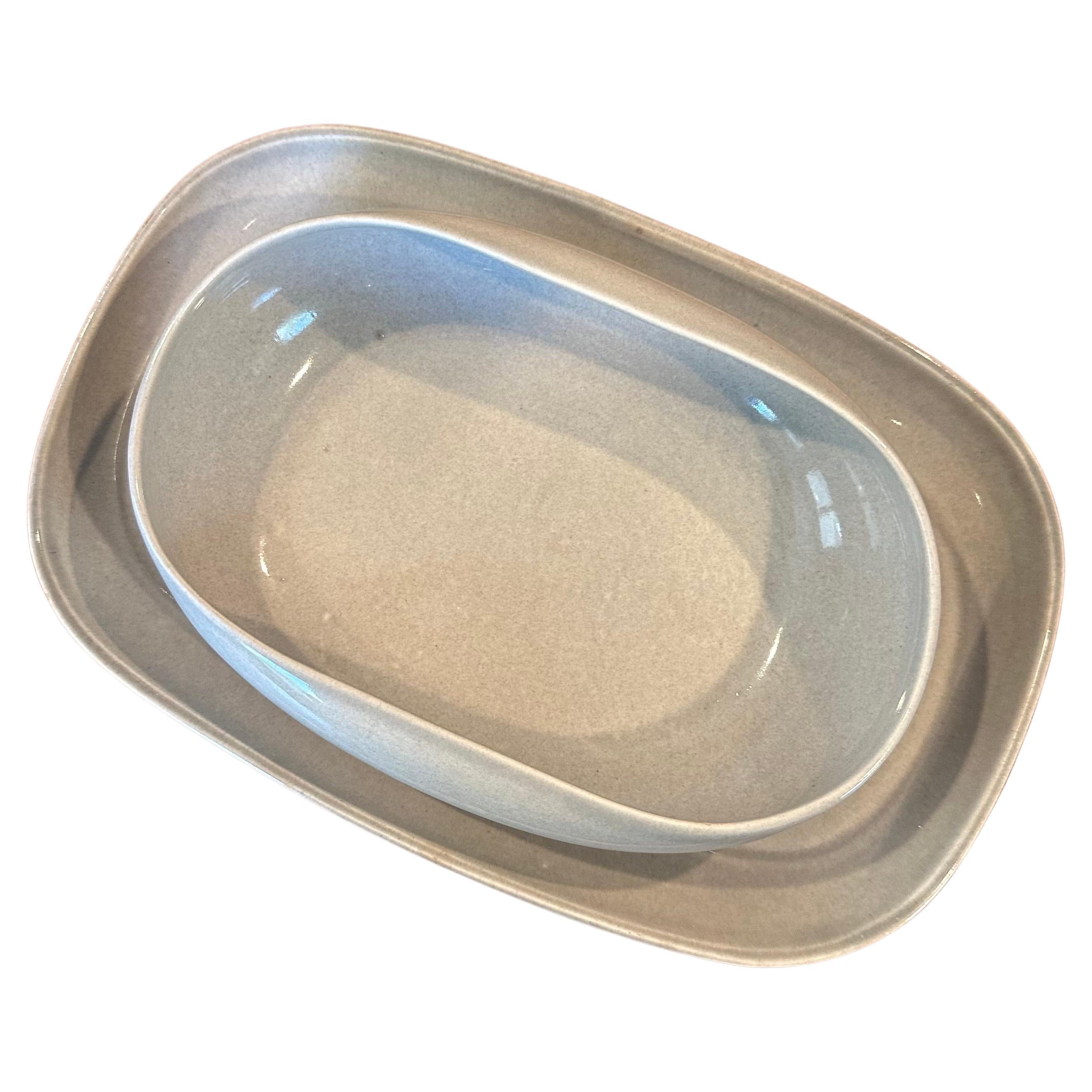 Stylish and functional American modern ceramic serving bowl and tray by Russel Wright for Steubenville Pottery of Ohio, circa 1940s. The ultramodern design emphasizes soft cures and simple glazing. The set is in very good vintage contain with no