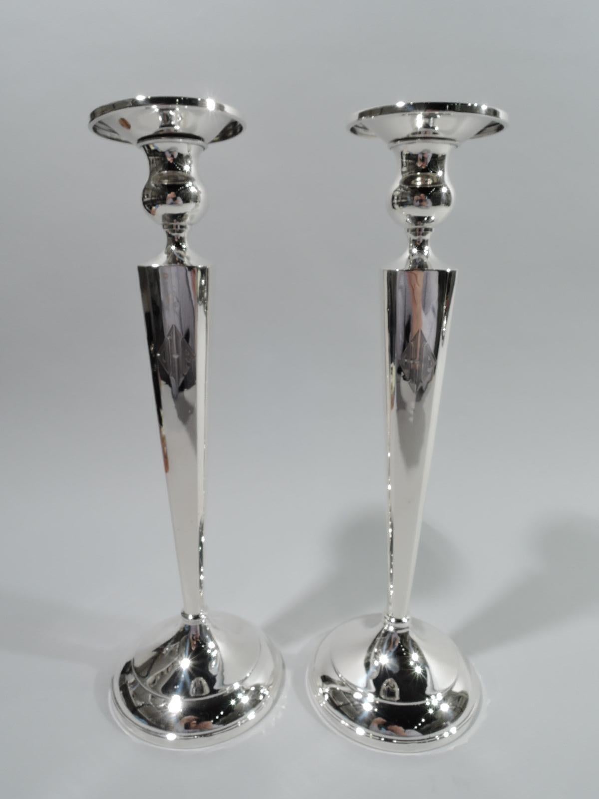 Pair of American Modern classical sterling silver candlesticks, ca 1940. Each: Tapering and chamfered pillar on domed foot. Bellied socket and detachable bobeche. Three-letter monogram. Marked “Sterling”. Weighted.