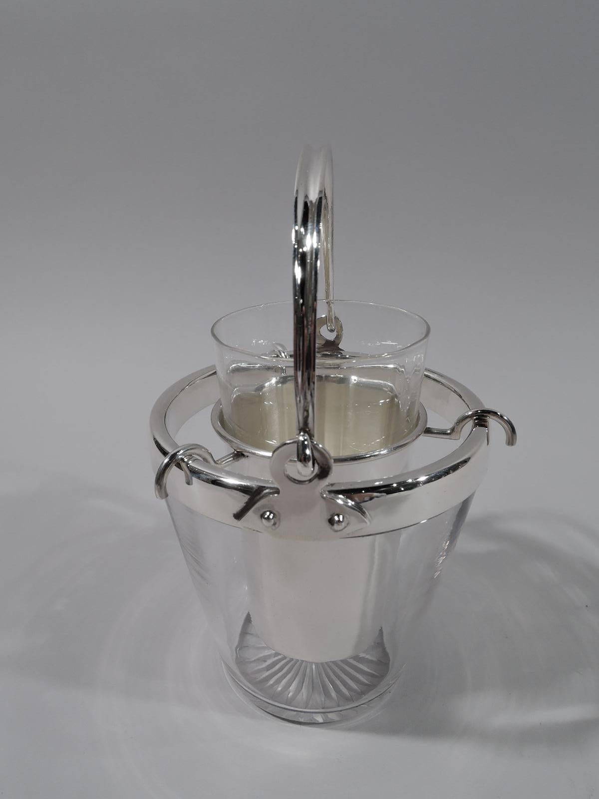 American Modern sterling silver and glass bowl, circa 1910. Tapering glass bucket with star cut to underside. Collar sterling silver as is c-scroll swing handle mounted to studded Craftsman-style mounts. Tall and tapering bowl attaches to rim with 3