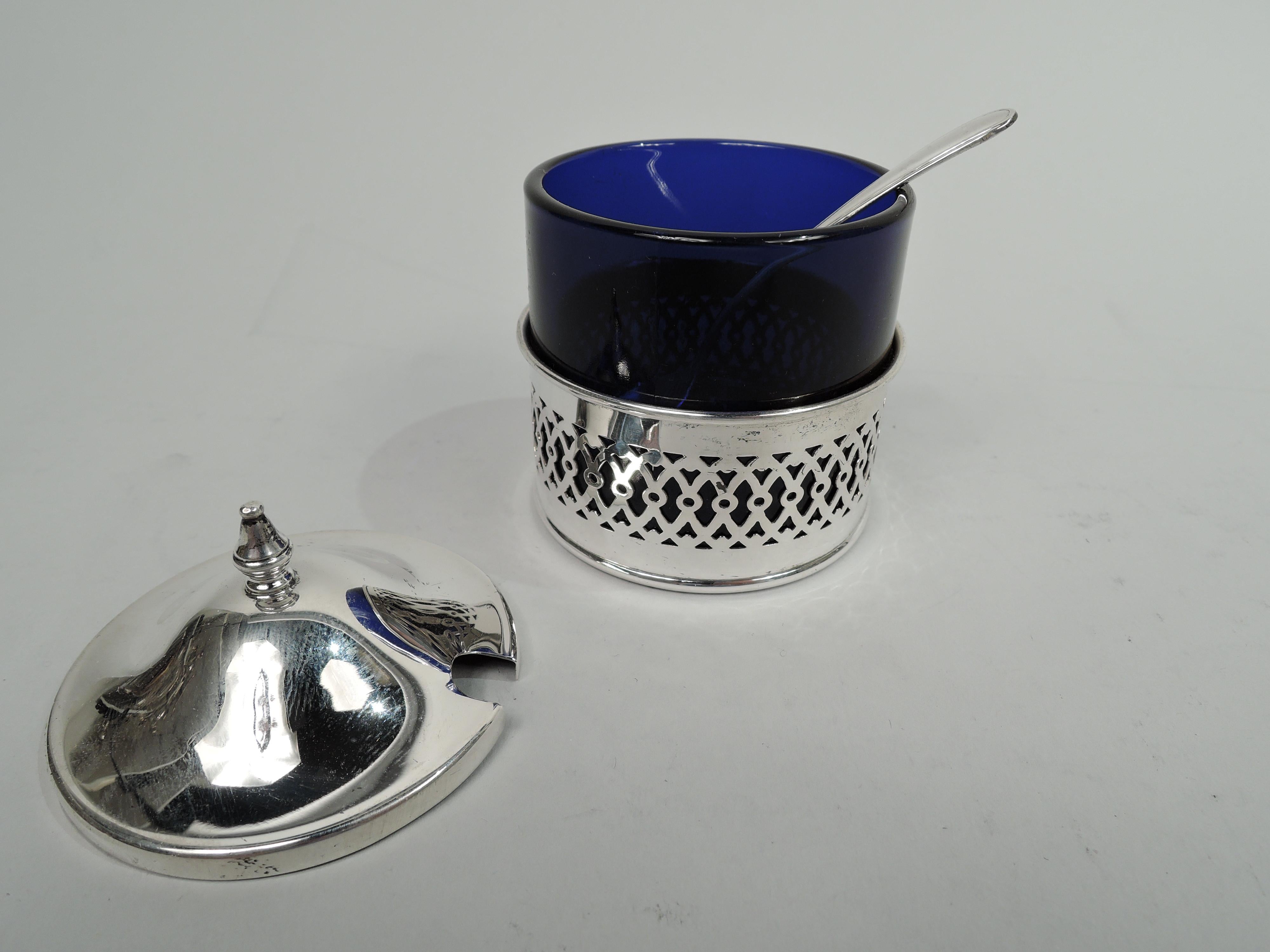 Modern Georgian sterling silver mustard pot. Made by Webster Company in North Attleboro, Mass., ca 1950. Cobalt glass bowl set in sterling silver base with pierced ornamental band. Cover raised with vasiform finial. With spoon. Base and spoon marked